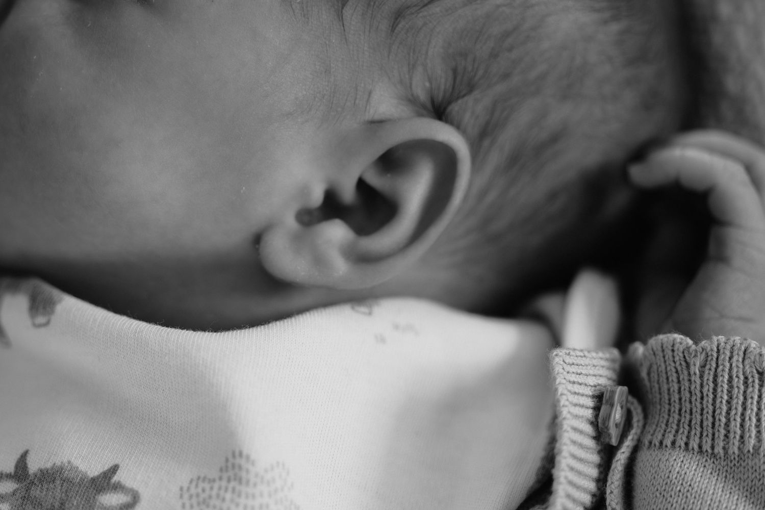 Close-up black and white photo of a sleeping newborn baby's ear and profile.