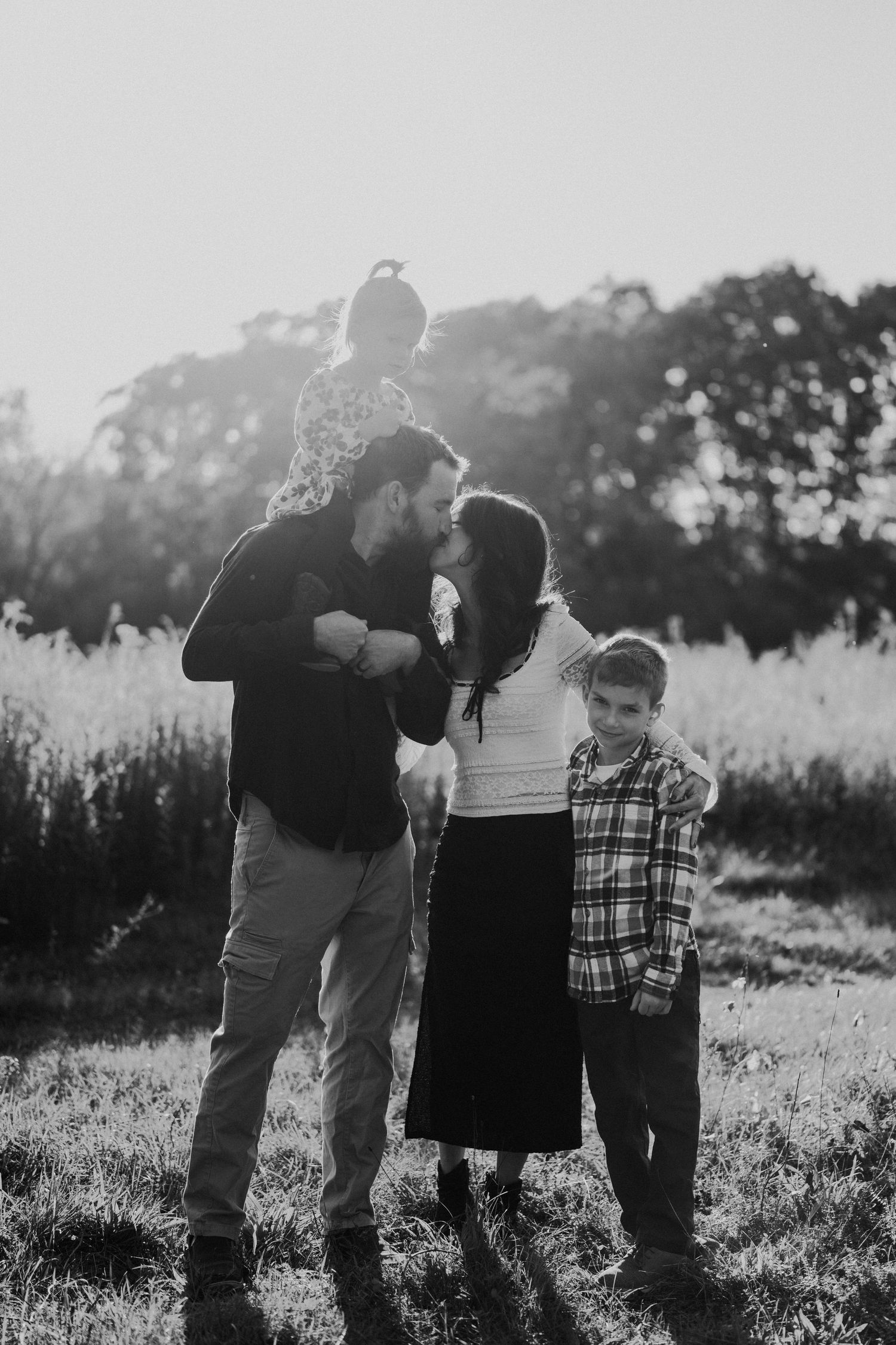 Family sharing a joyful moment together in a sunlit meadow.