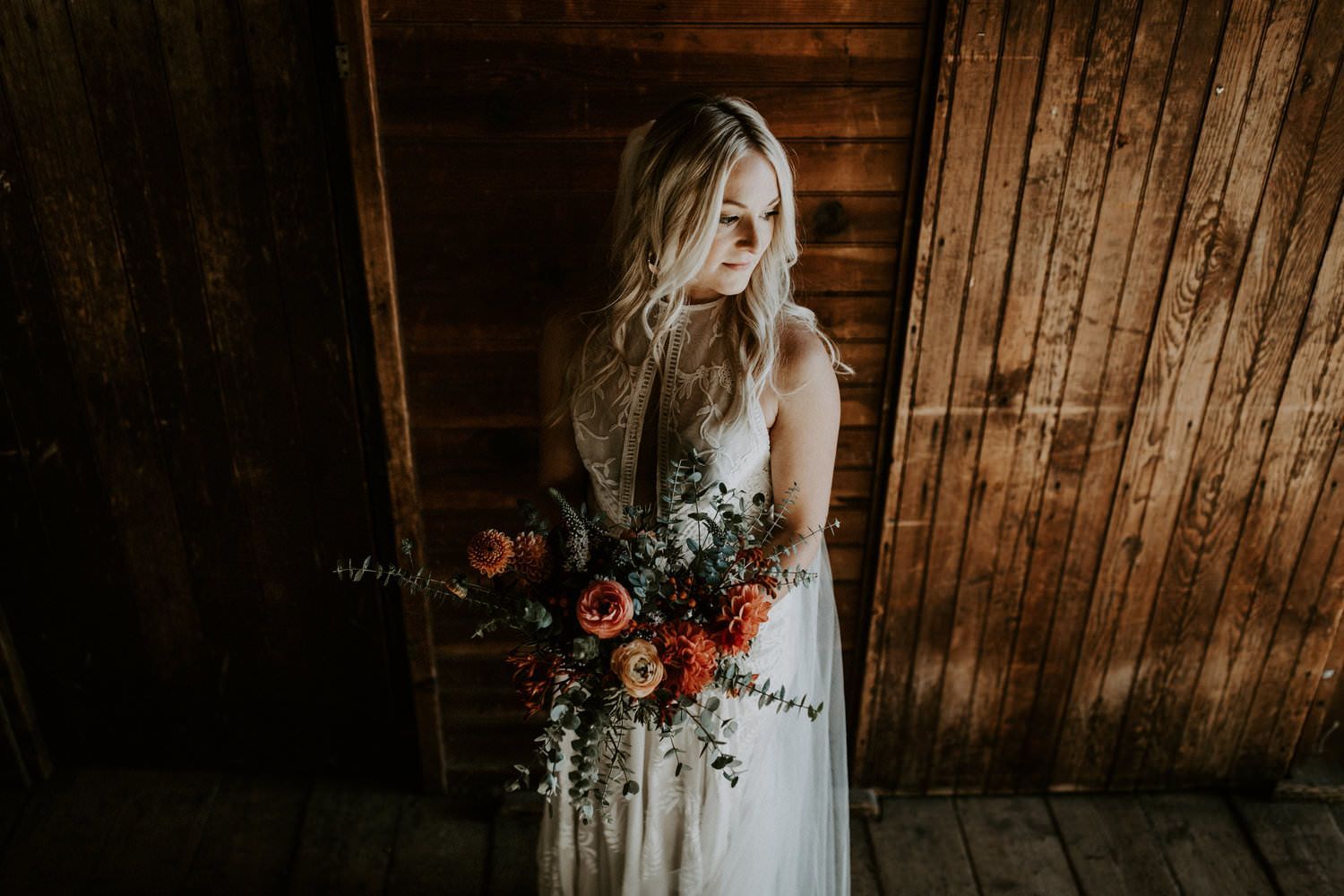 Rustic wooden backdrop frames elegant bridal portrait with floral details.