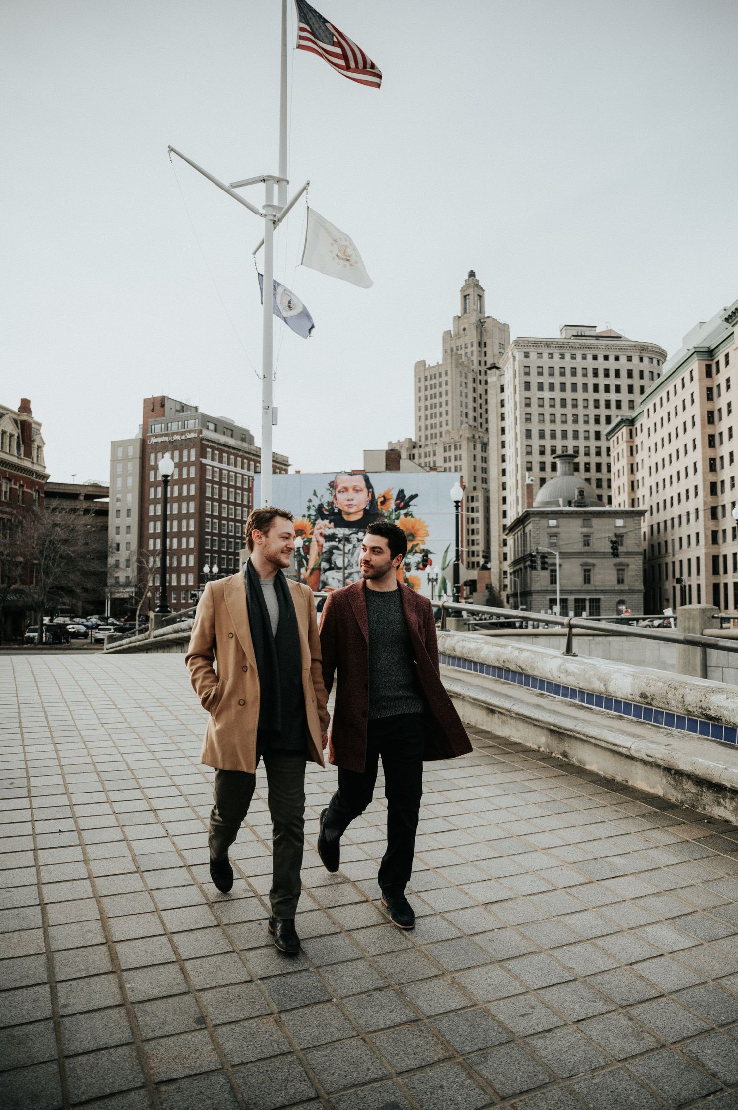 Group walking along urban sidewalk with American flags and historic buildings in the background.
