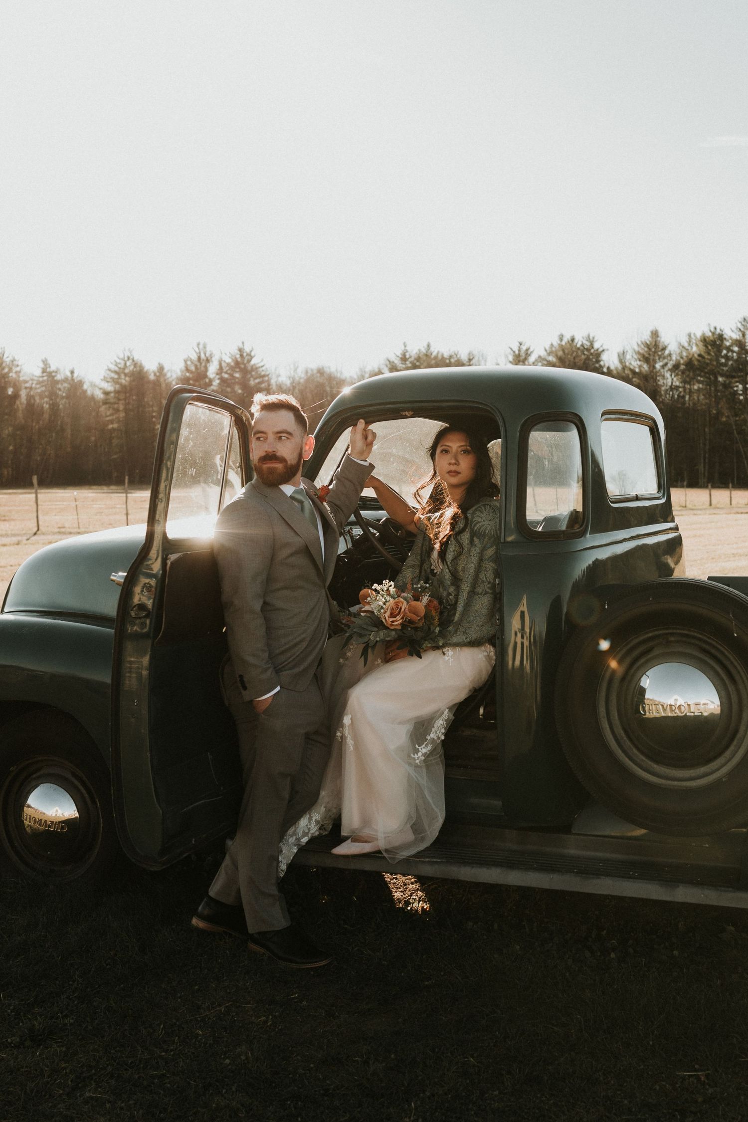 Couple poses with vintage truck during sunset wedding photoshoot.