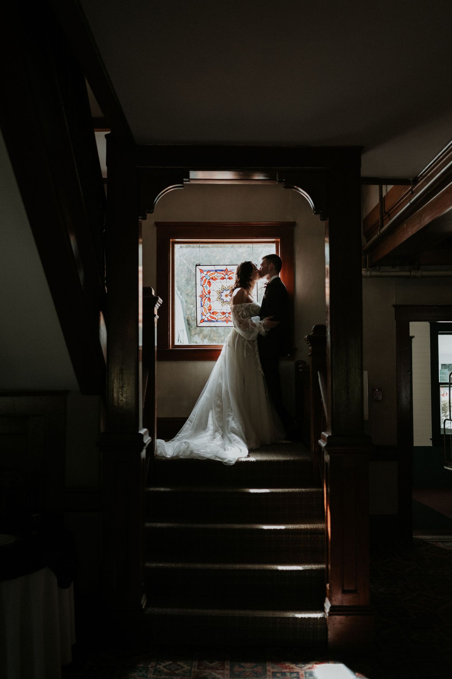 A silhouetted couple shares an intimate moment on a dark staircase.