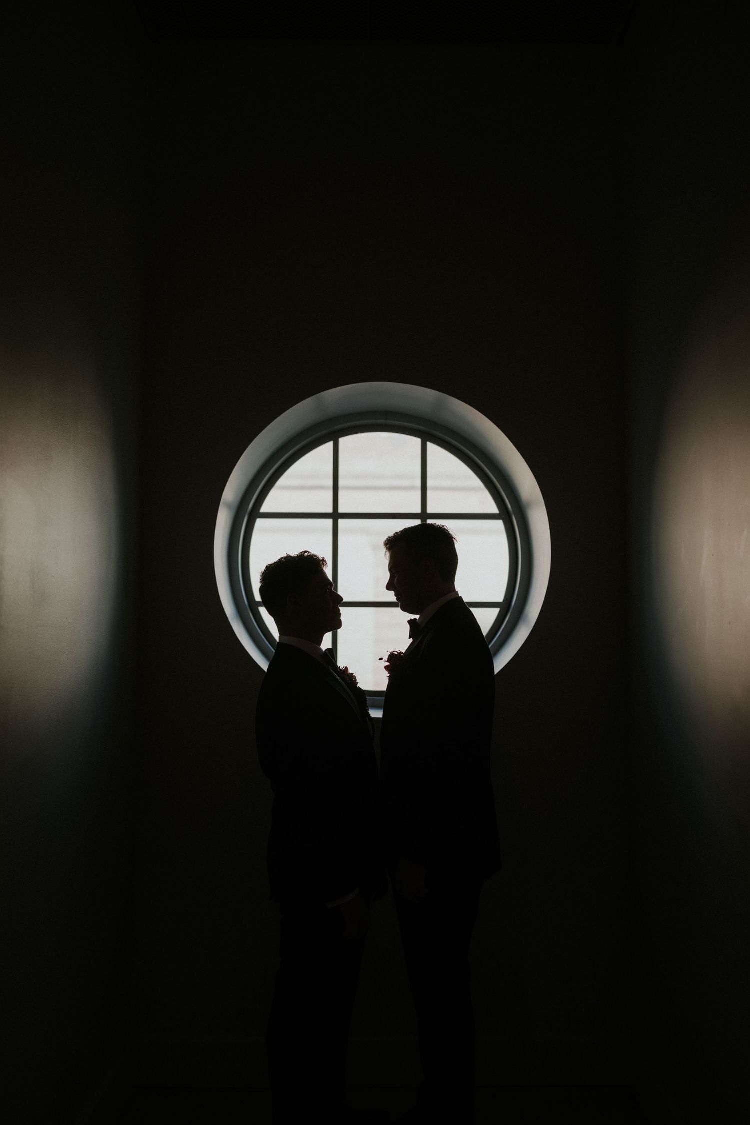 Silhouettes framed in circular window create dramatic composition against bright background.