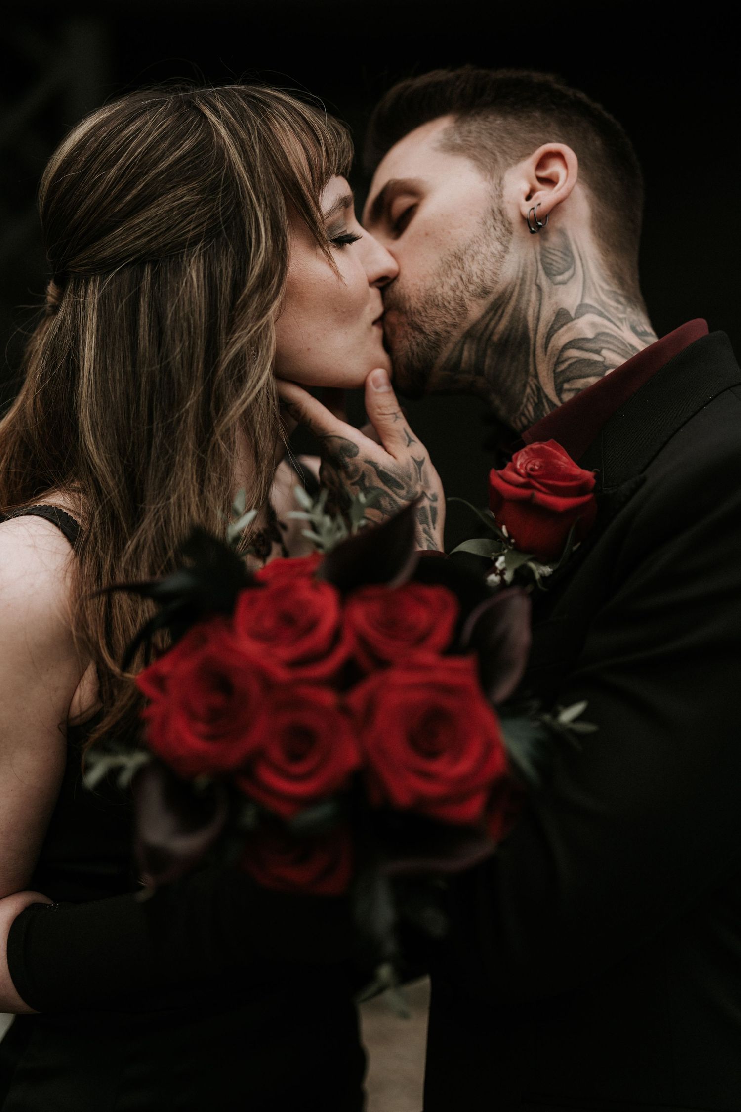 Romantic couple sharing intimate kisses with vibrant red roses in the foreground.