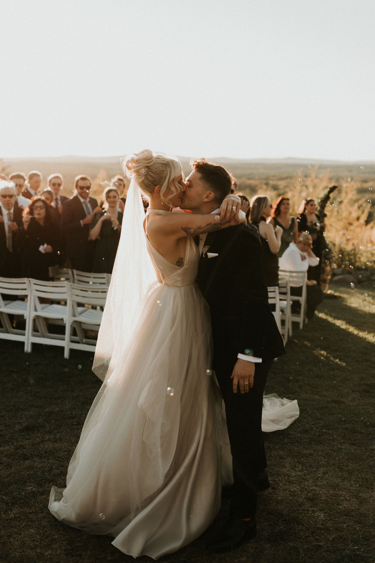 Newlyweds share their first dance at an outdoor sunset wedding ceremony.