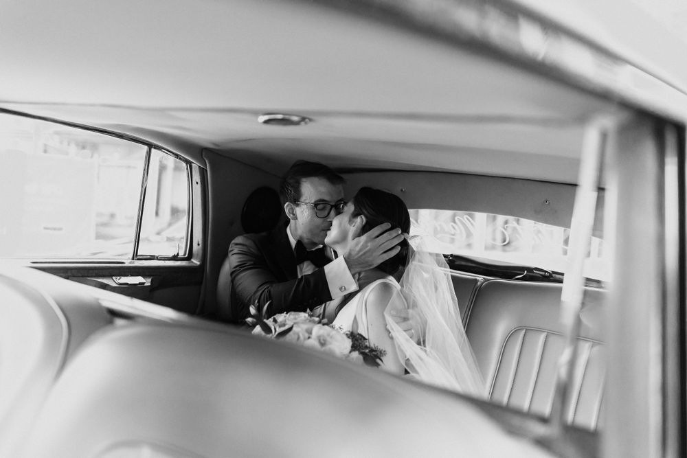 Black and white interior of vintage car with romantic couple silhouetted against window.