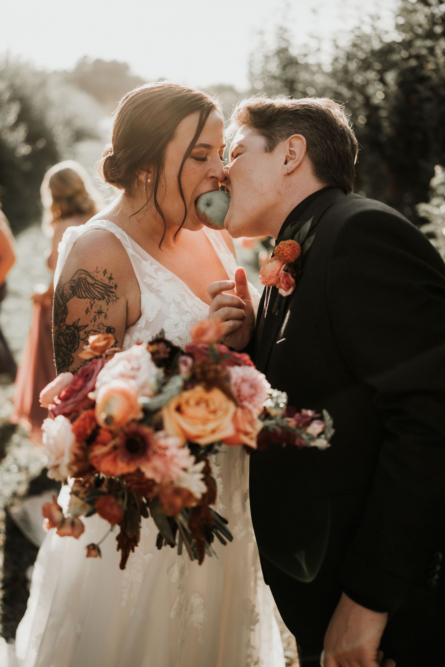 Wedding couple with vibrant coral and pink bouquet sharing an intimate moment.
