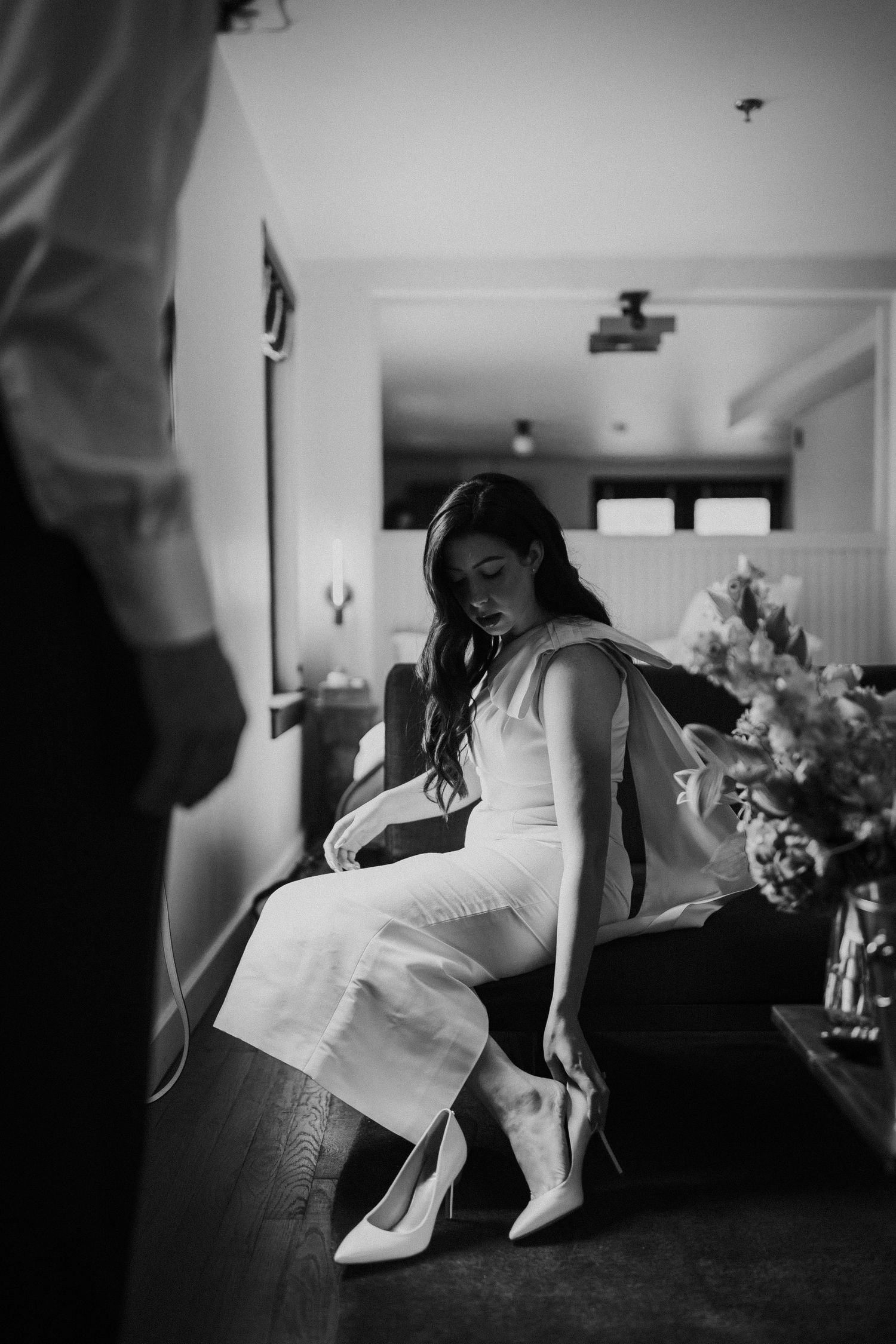 Black and white photo of someone in a white dress sitting on a couch in casual motion.