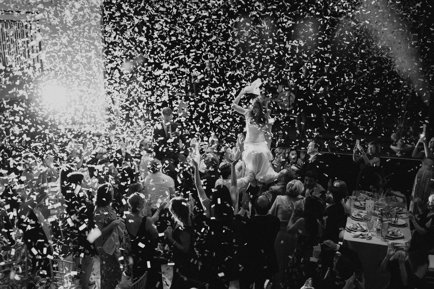 Black and white photo of crowd celebrating with confetti falling from above.