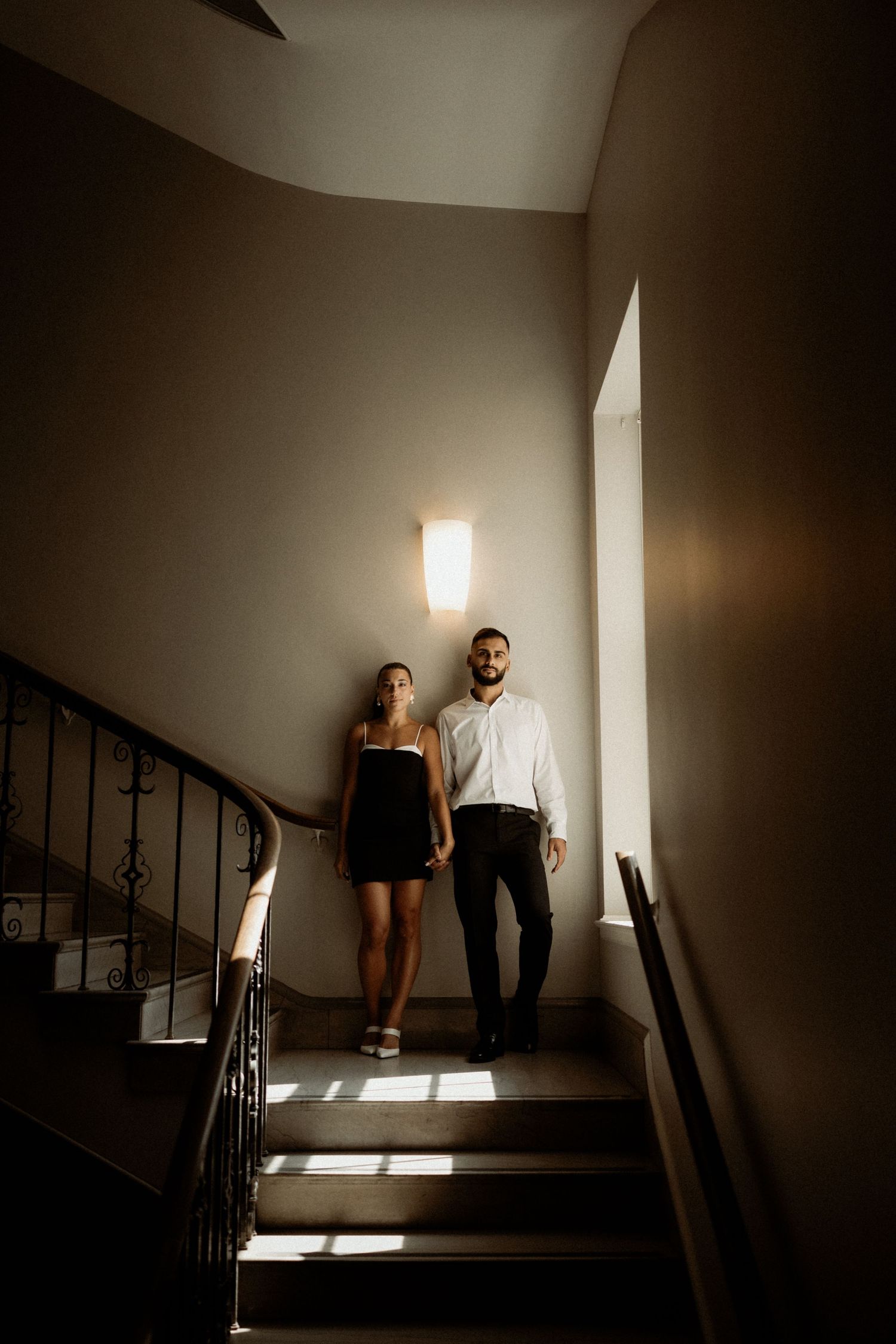 Dramatic lighting illuminates a stairwell with dark shadows and architectural details.