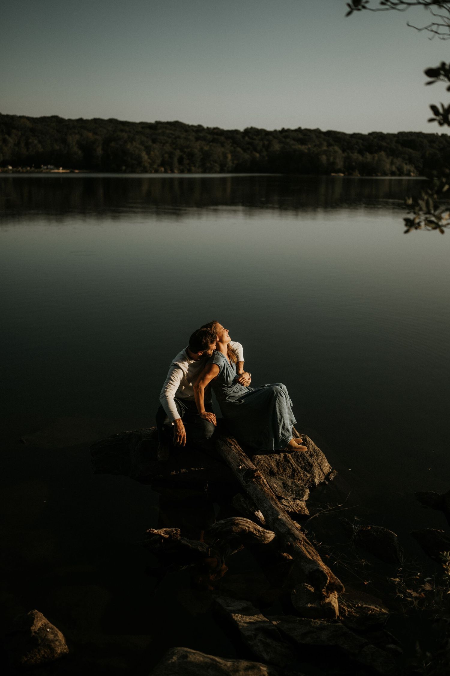 Moody lakeside scene with rocks and water during sunset.