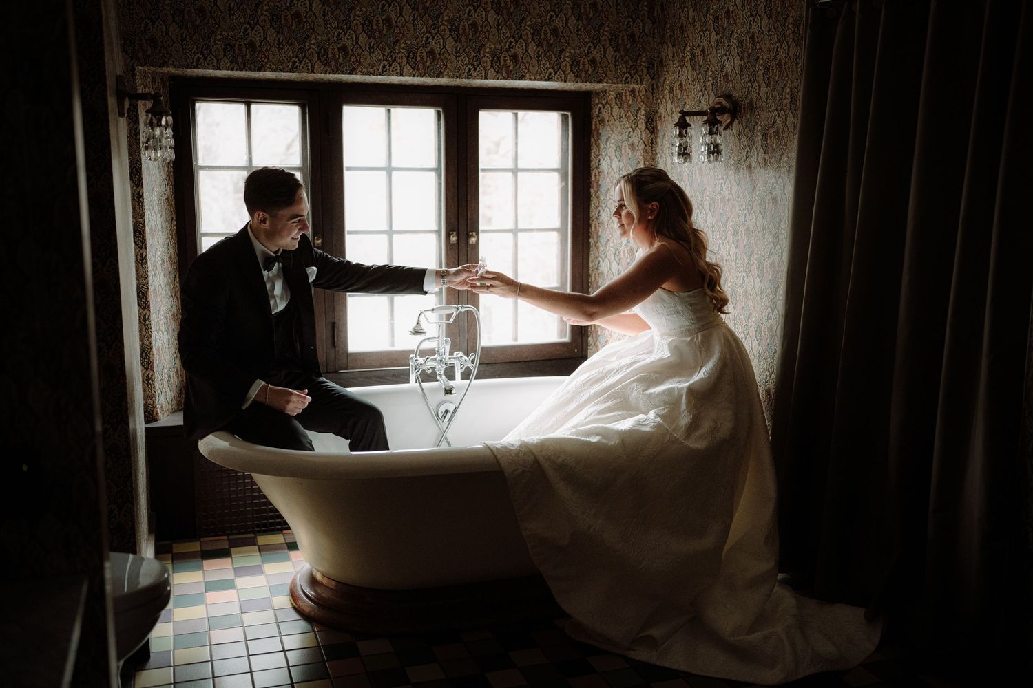 Dramatic silhouette of a bride in a flowing dress against bright window light.