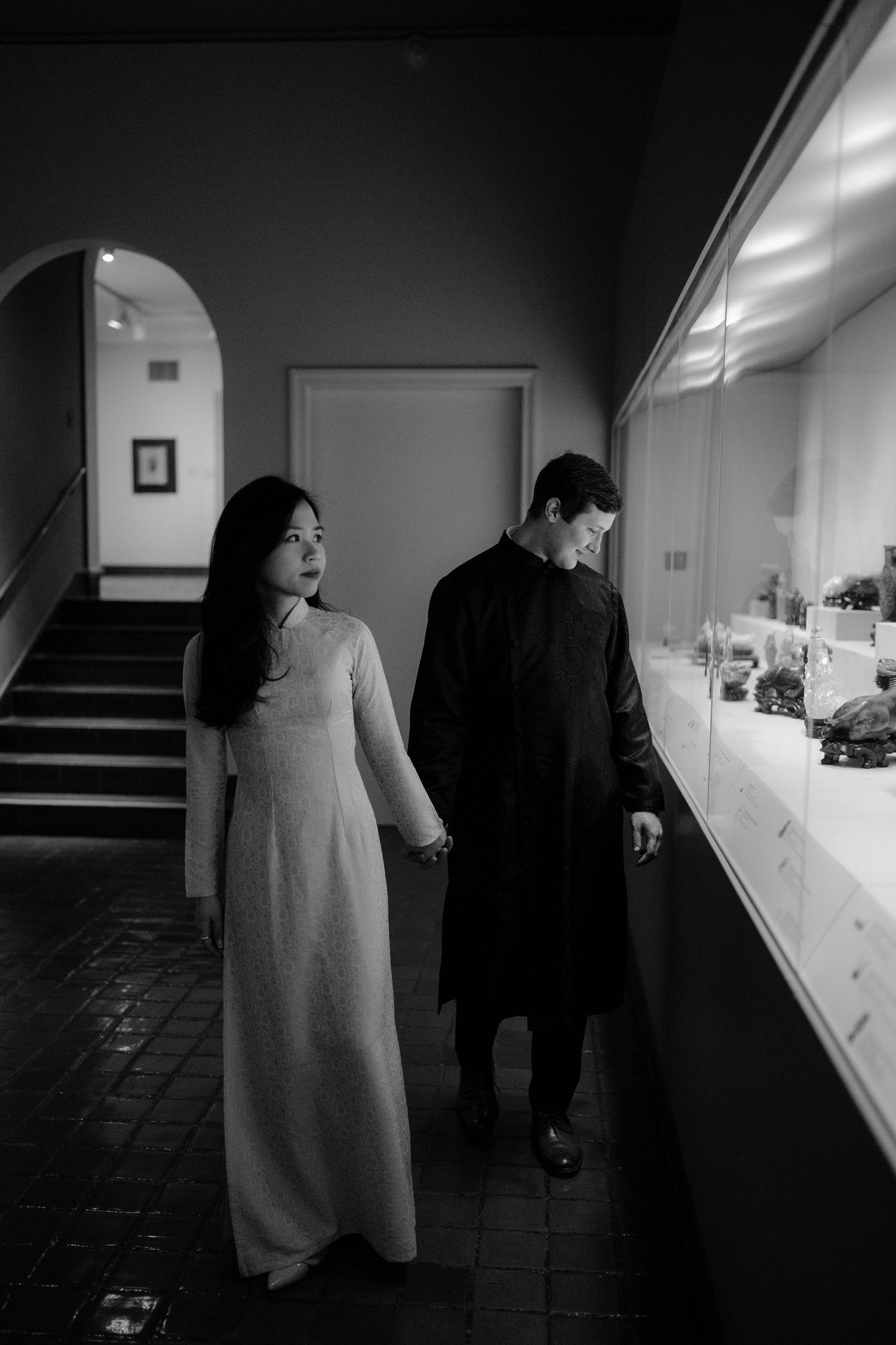 Black and white photo sequence showing two people examining items in a dimly lit hallway.