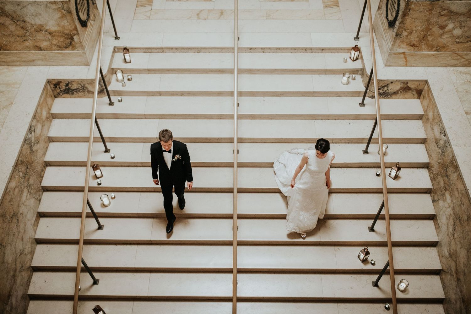 Wedding couple descending grand stone steps in dramatic black and white photography.