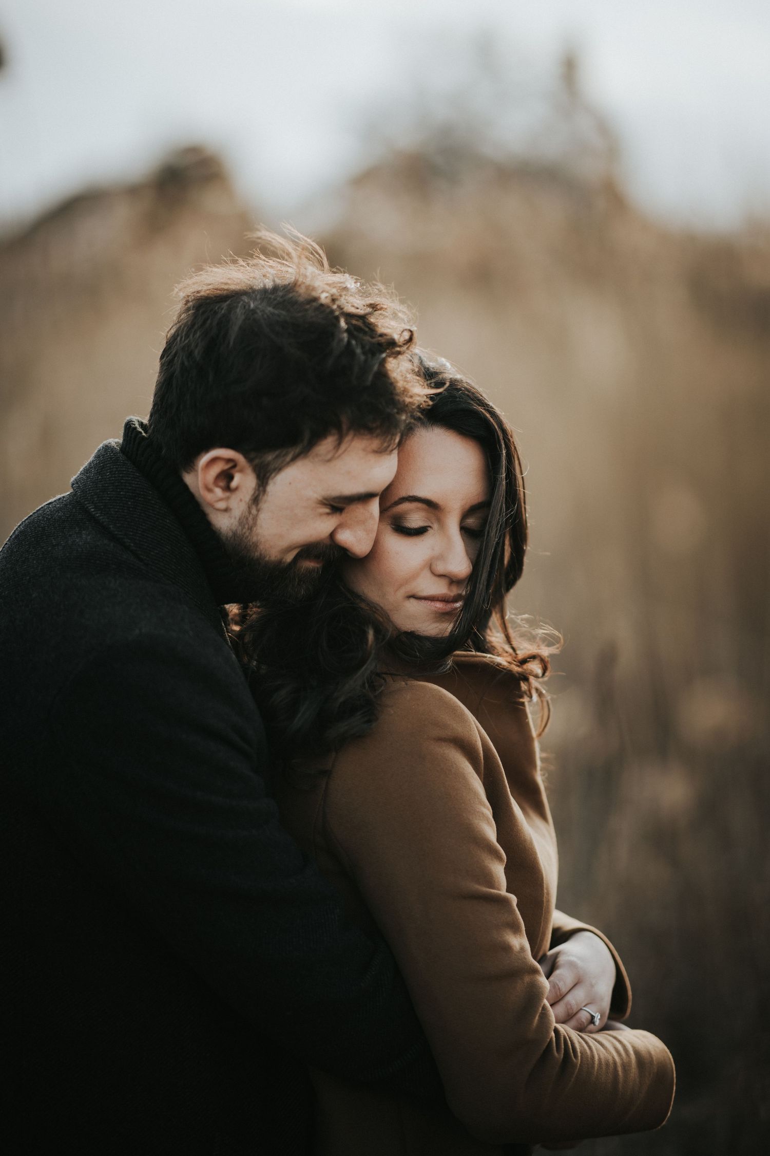 A cozy autumn photoshoot of a couple sharing tender moments outdoors at sunset.