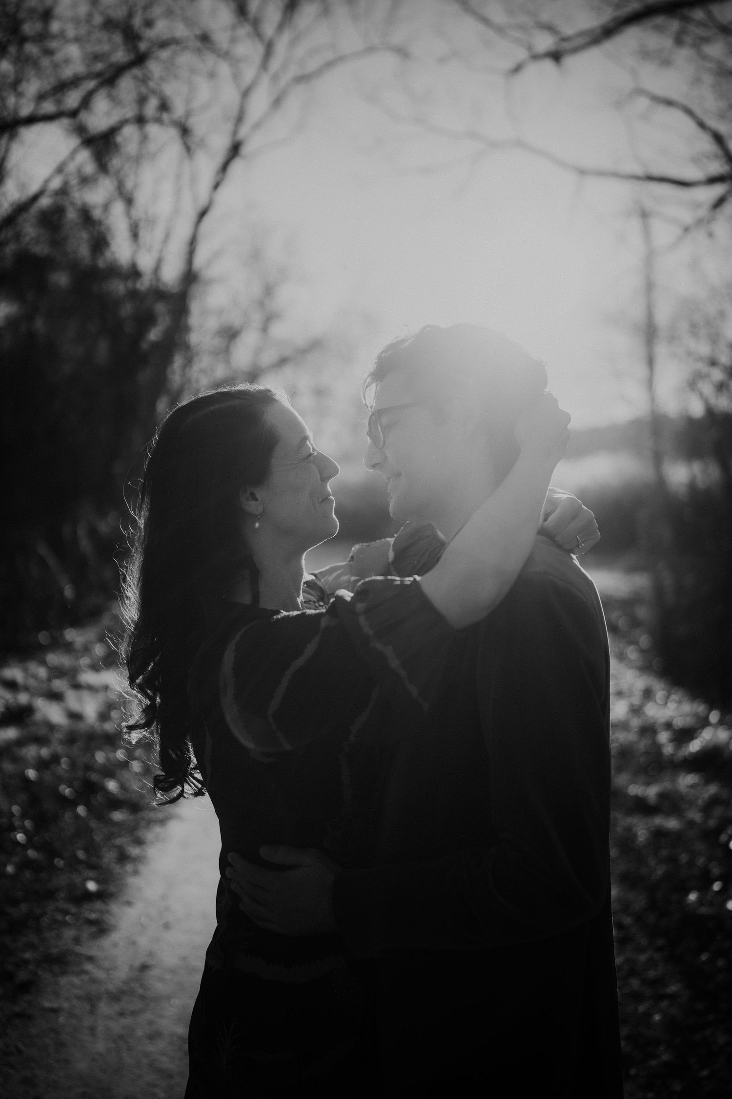 A silhouetted couple shares an intimate moment in front of a sunlit background.