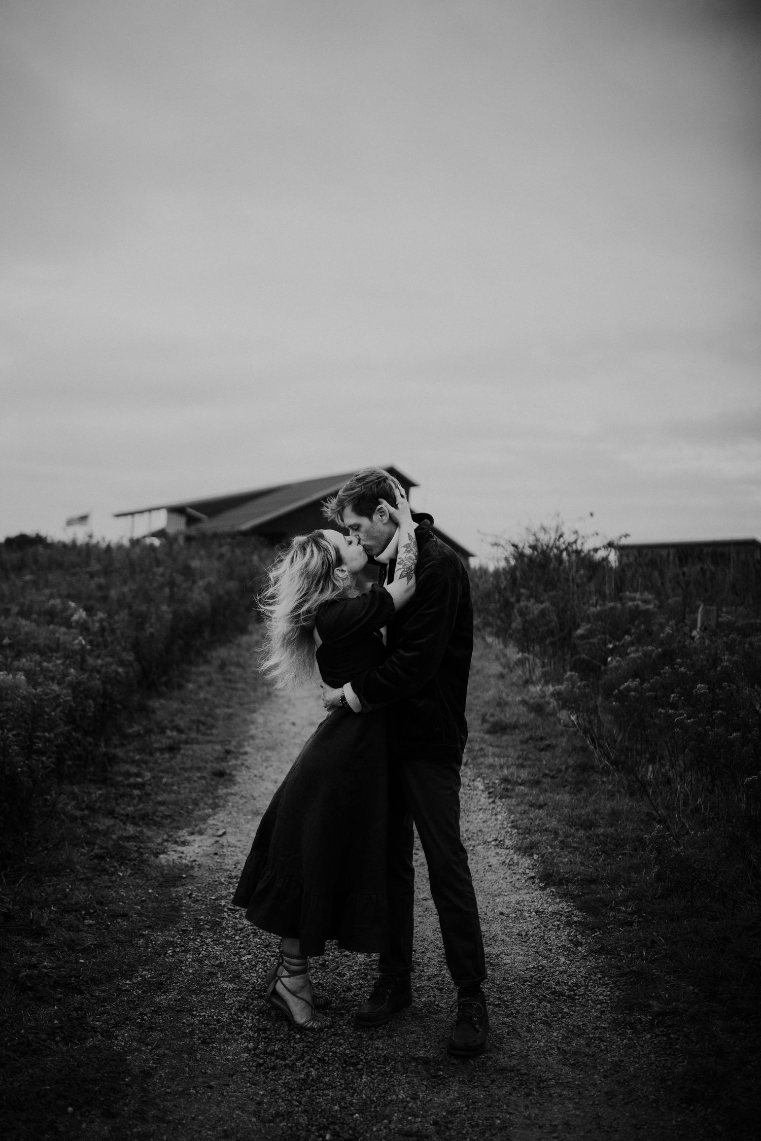 Romantic black and white silhouette of a couple embracing on a rural path.
