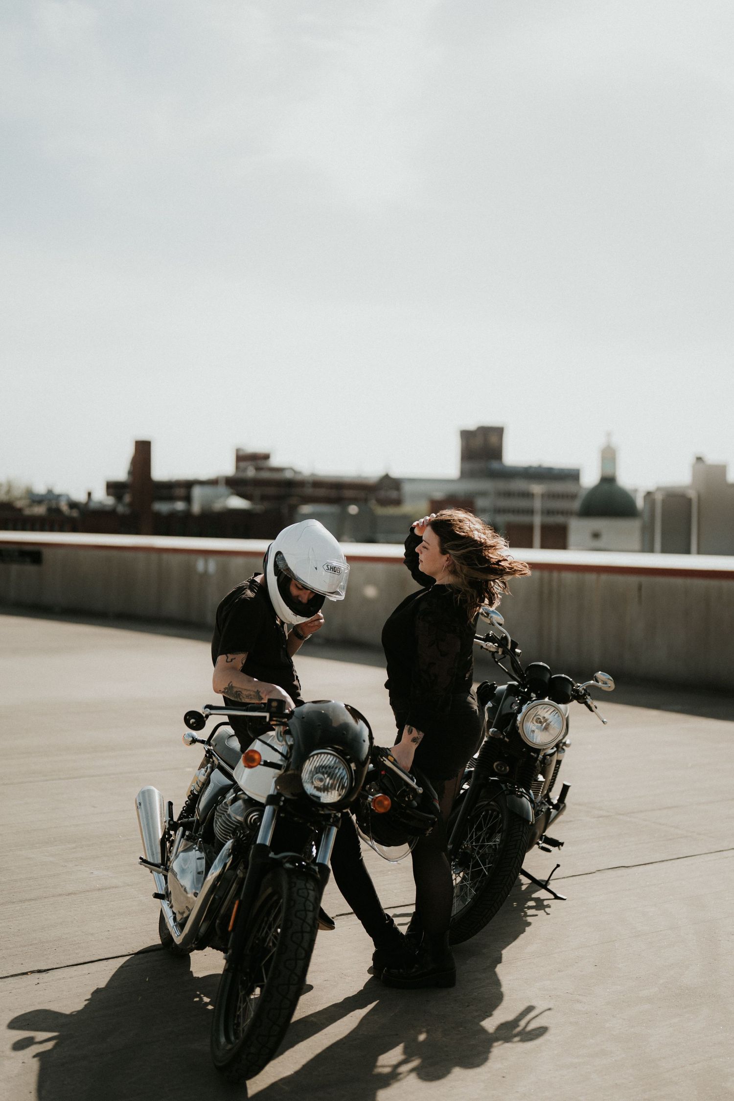 Vintage motorcycles parked on rooftop against urban skyline.