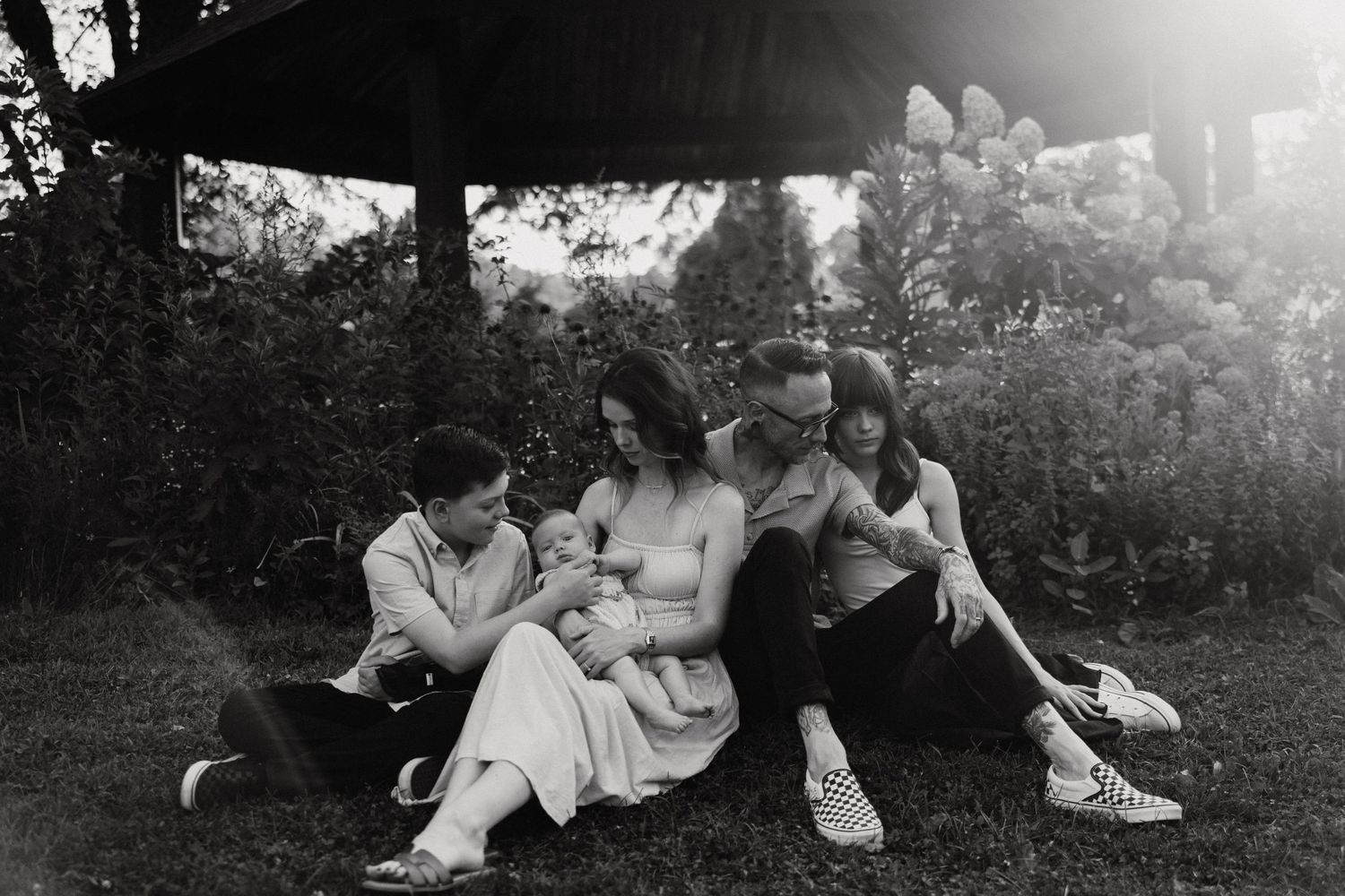 Group relaxing together under gazebo in casual black and white photograph.