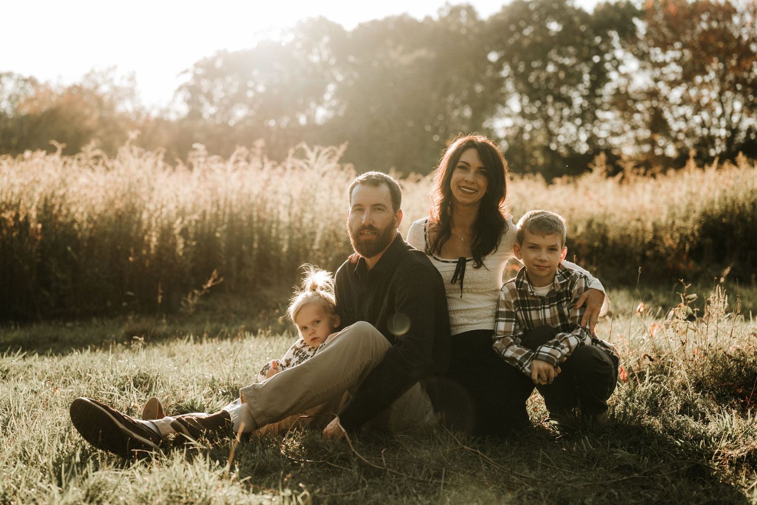 Family relaxing together in a sunlit field at golden hour.