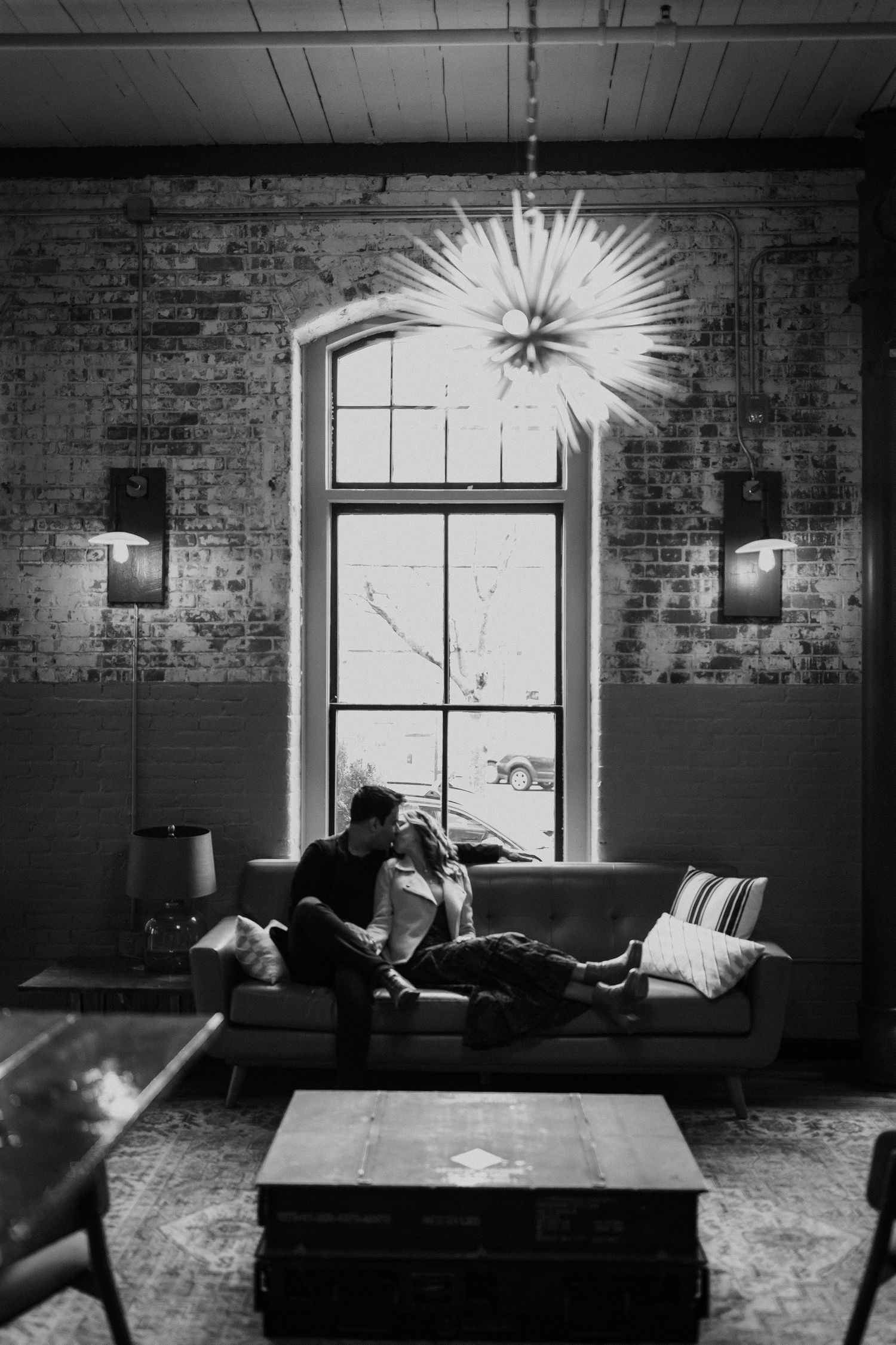 Artistic black and white sequence showing movement across an industrial room with exposed brick and bright windows.