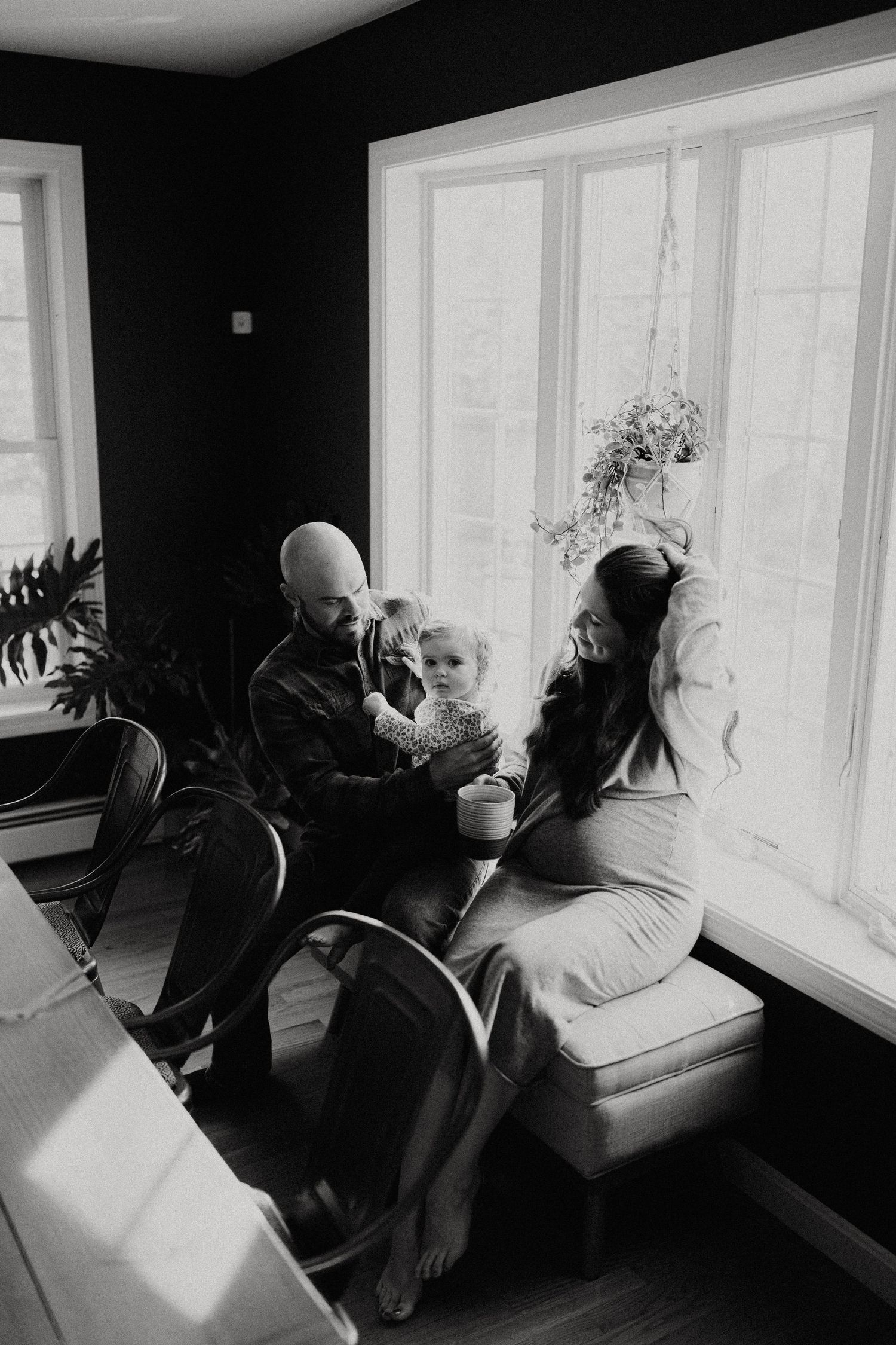 Black and white photo series of people lounging by bright windows.