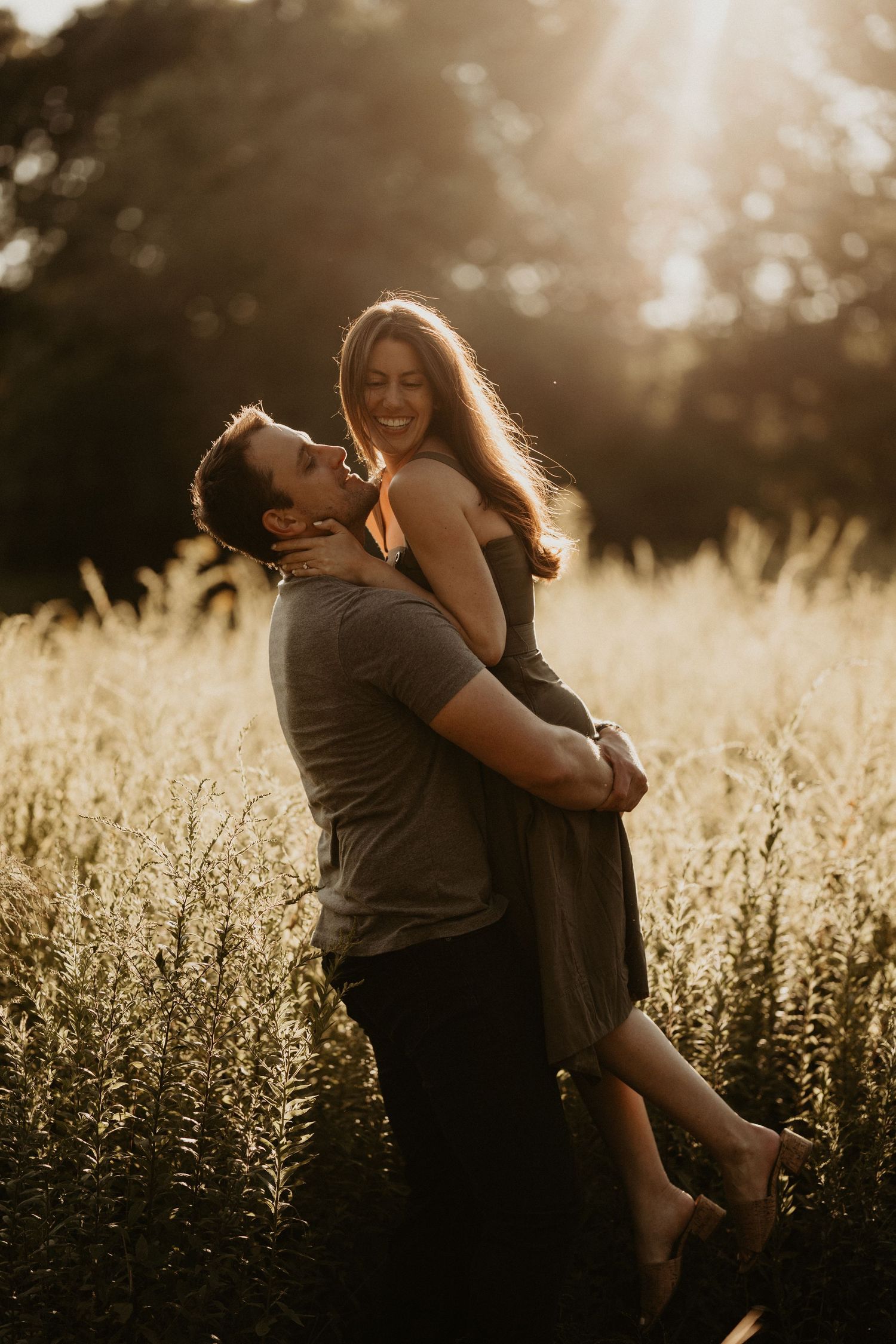 Romantic couple embracing in a sunlit field during golden hour.