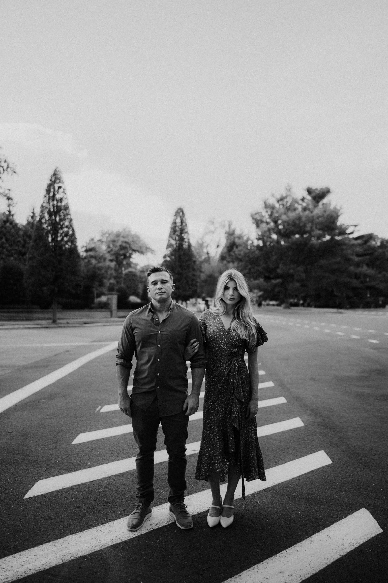 Black and white photo of people standing on crosswalk markings in an empty parking lot.