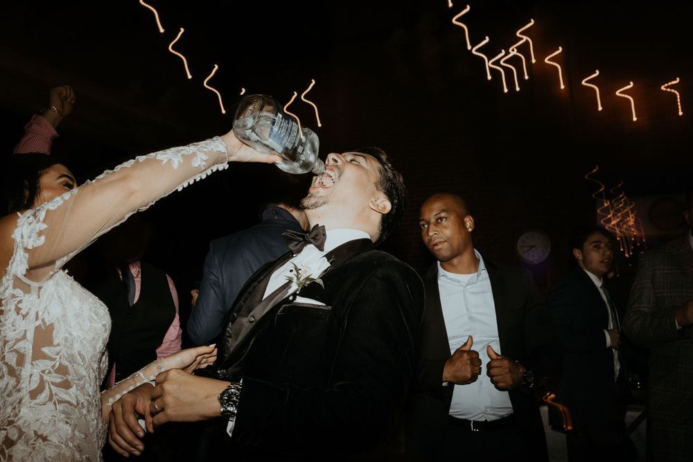 Wedding guests dance and celebrate on a dark dance floor during a reception.