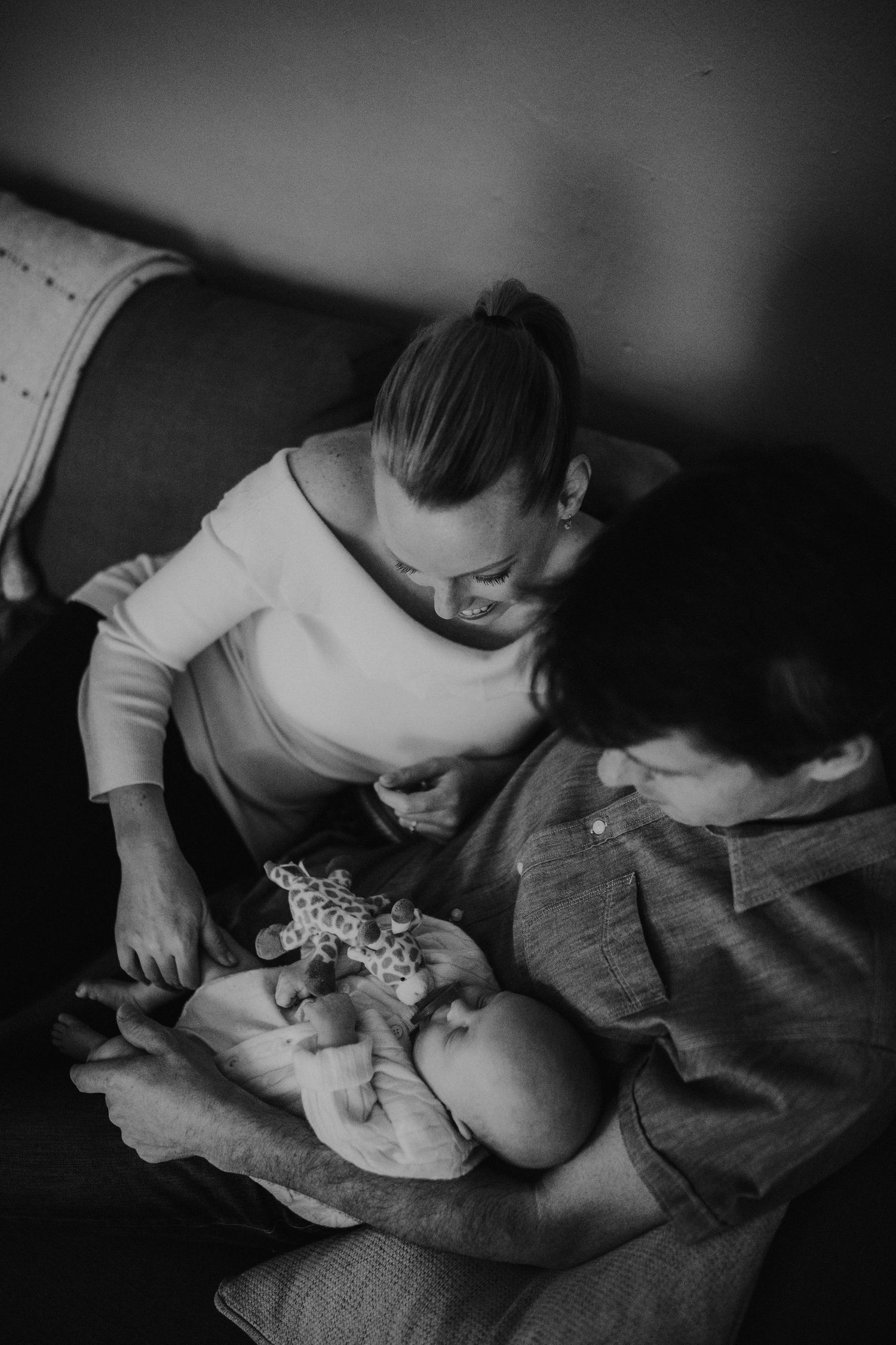 A tender black and white moment between parent and infant on a couch.