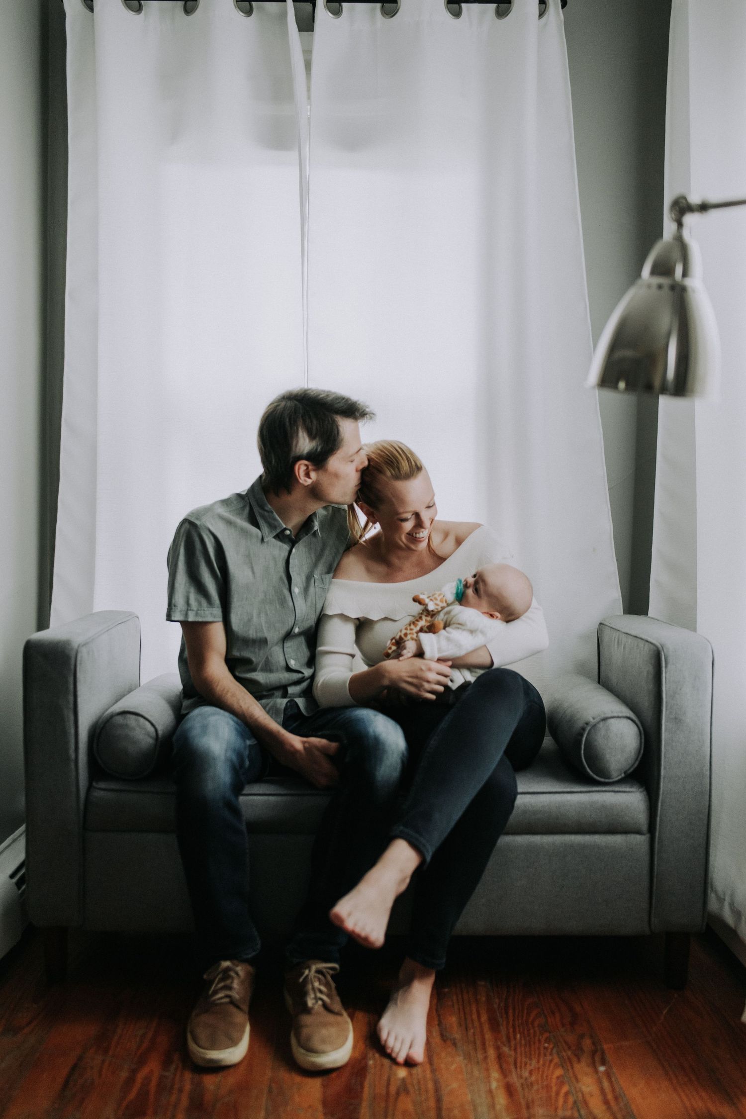 Intimate living room scene on grey couch with white curtains.