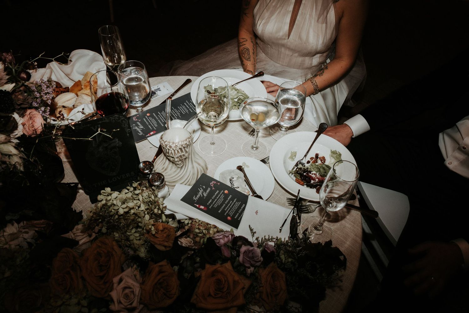 Overhead view of an elegant wedding reception dinner table setting in dim lighting.