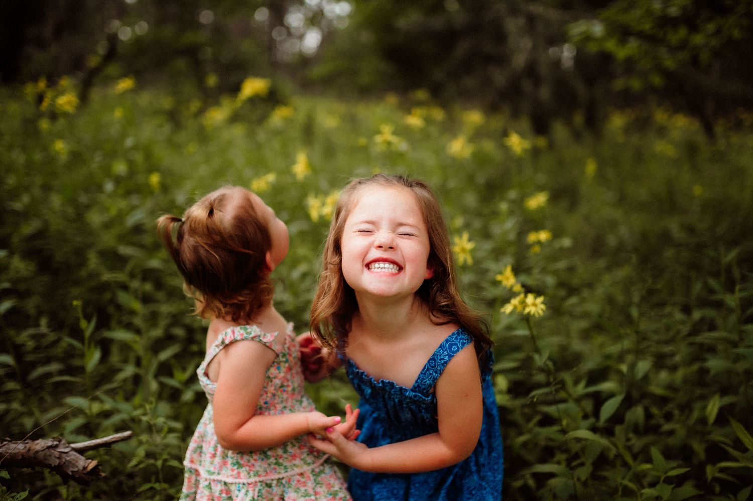 A joyful moment captured in a lush green garden with yellow wildflowers blooming in the background.