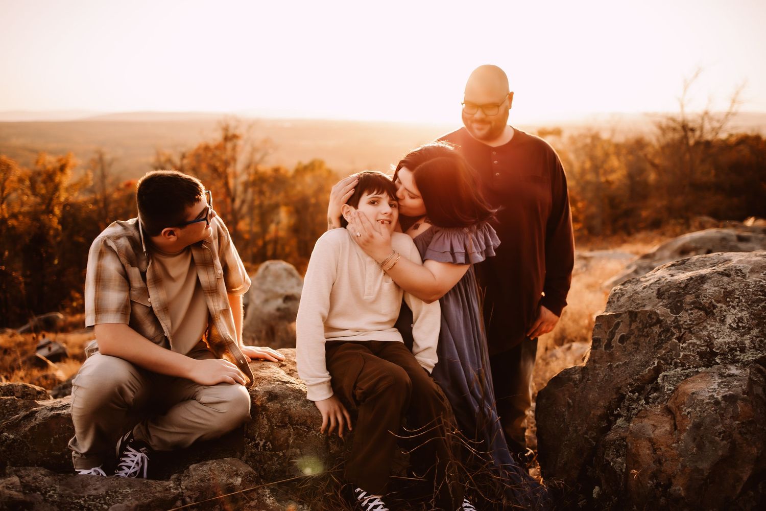 A couple shares intimate moments during a golden hour photoshoot in a natural outdoor setting.