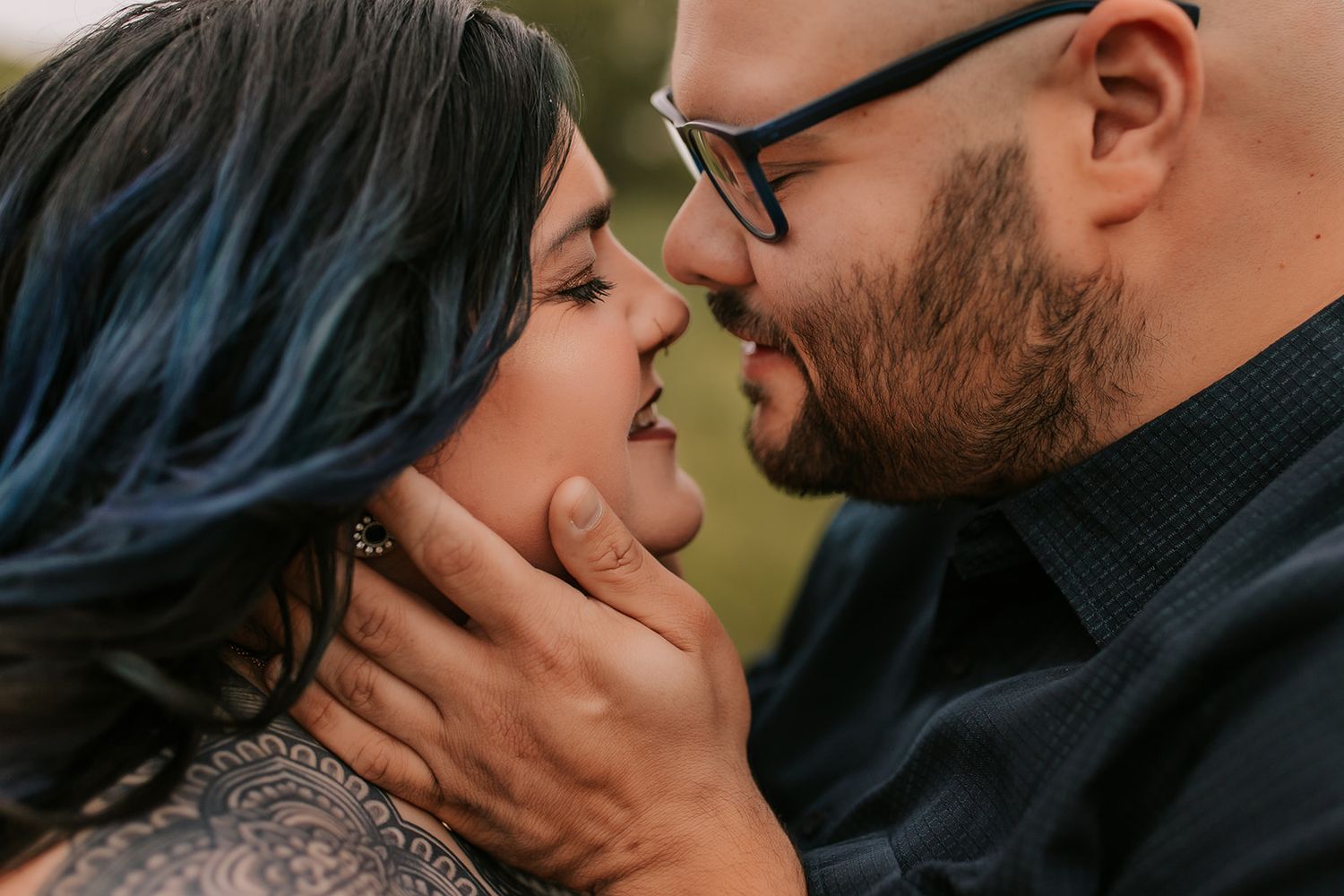 Close up romantic couple kissing in soft natural light with blurred outdoor background.