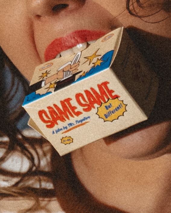 Woman with red lipstick holds a retro-style Same Same But Different film box between her teeth in a close-up portrait.