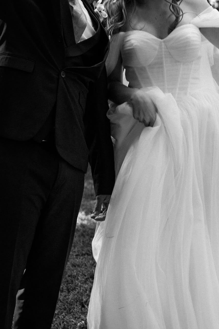Black and white close-up of bride in a strapless tulle gown walking arm in arm with the groom.
