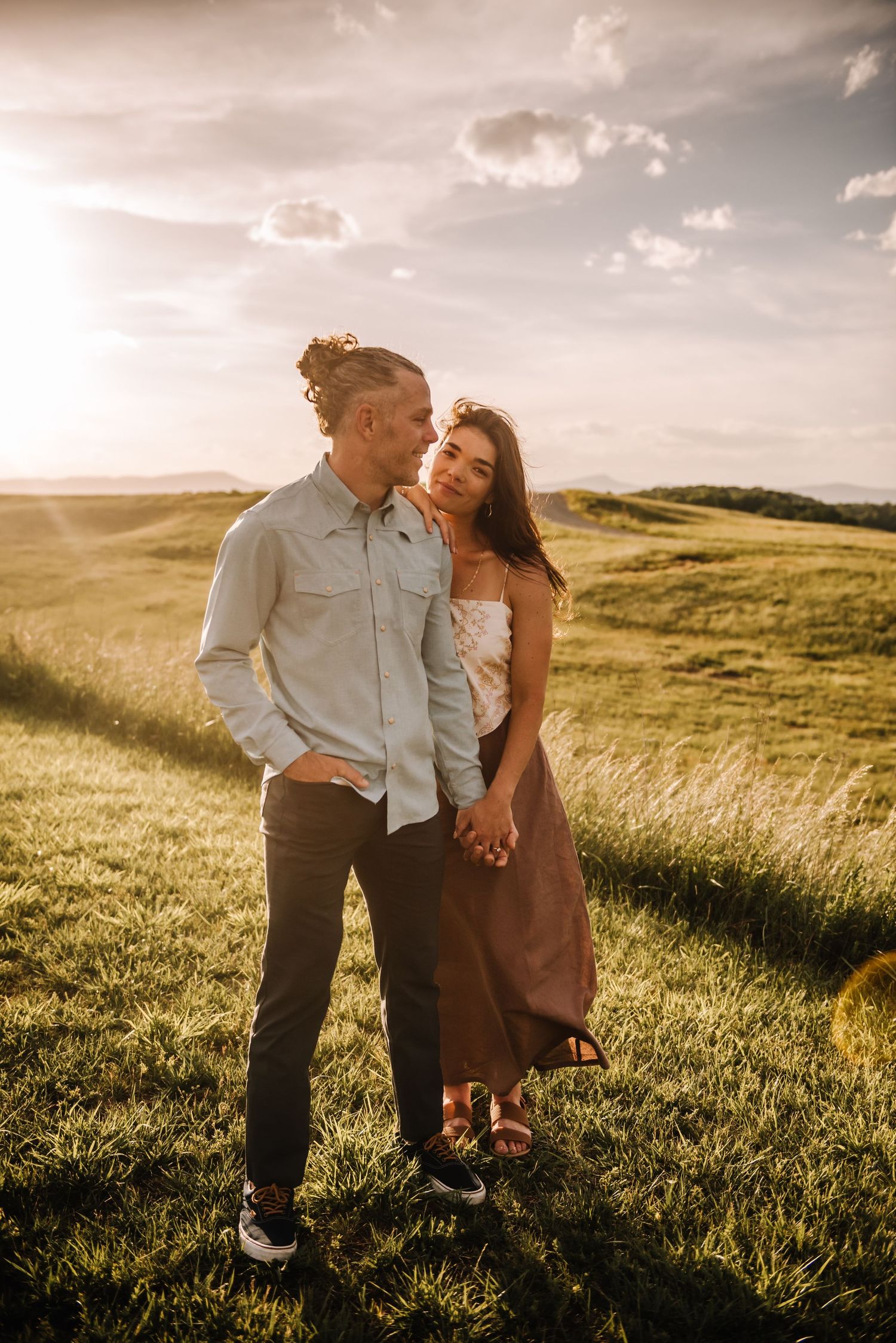 Engaged couple embracing on the Blue Ridge Parkway near Roanoke, Virginia with scenic mountain overlooks in the background.