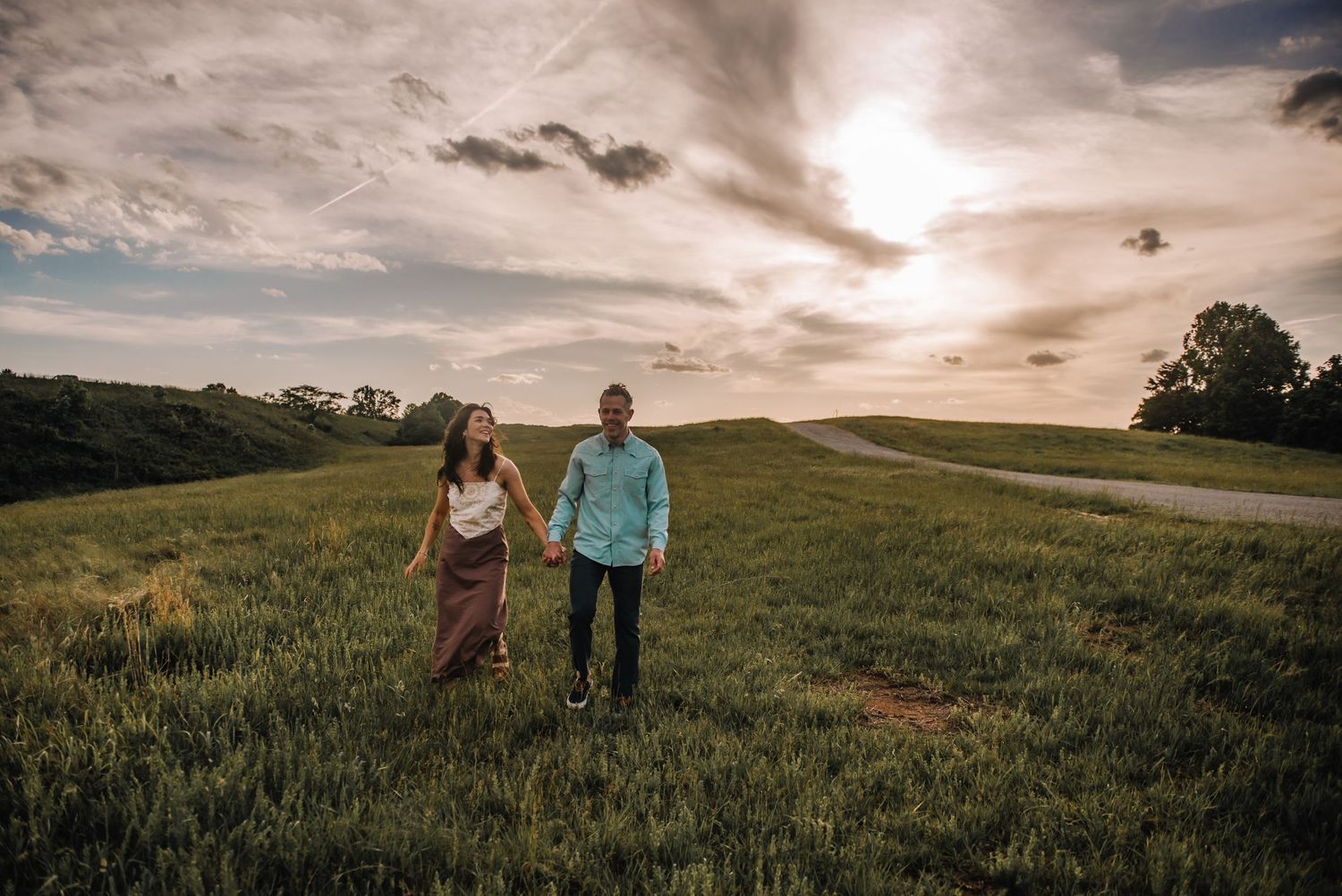 Romantic couples portrait on the Blue Ridge Parkway in Roanoke, Virginia featuring a couple walking together through the mountains at sunset
