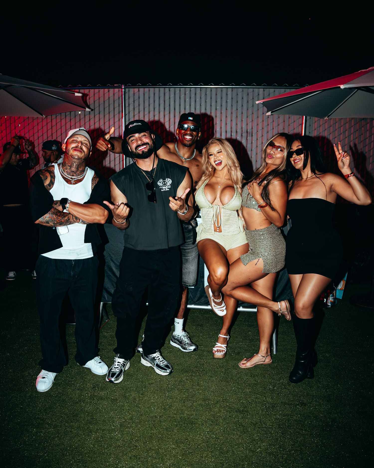 Group of friends posing and smiling together at an outdoor nighttime party event.