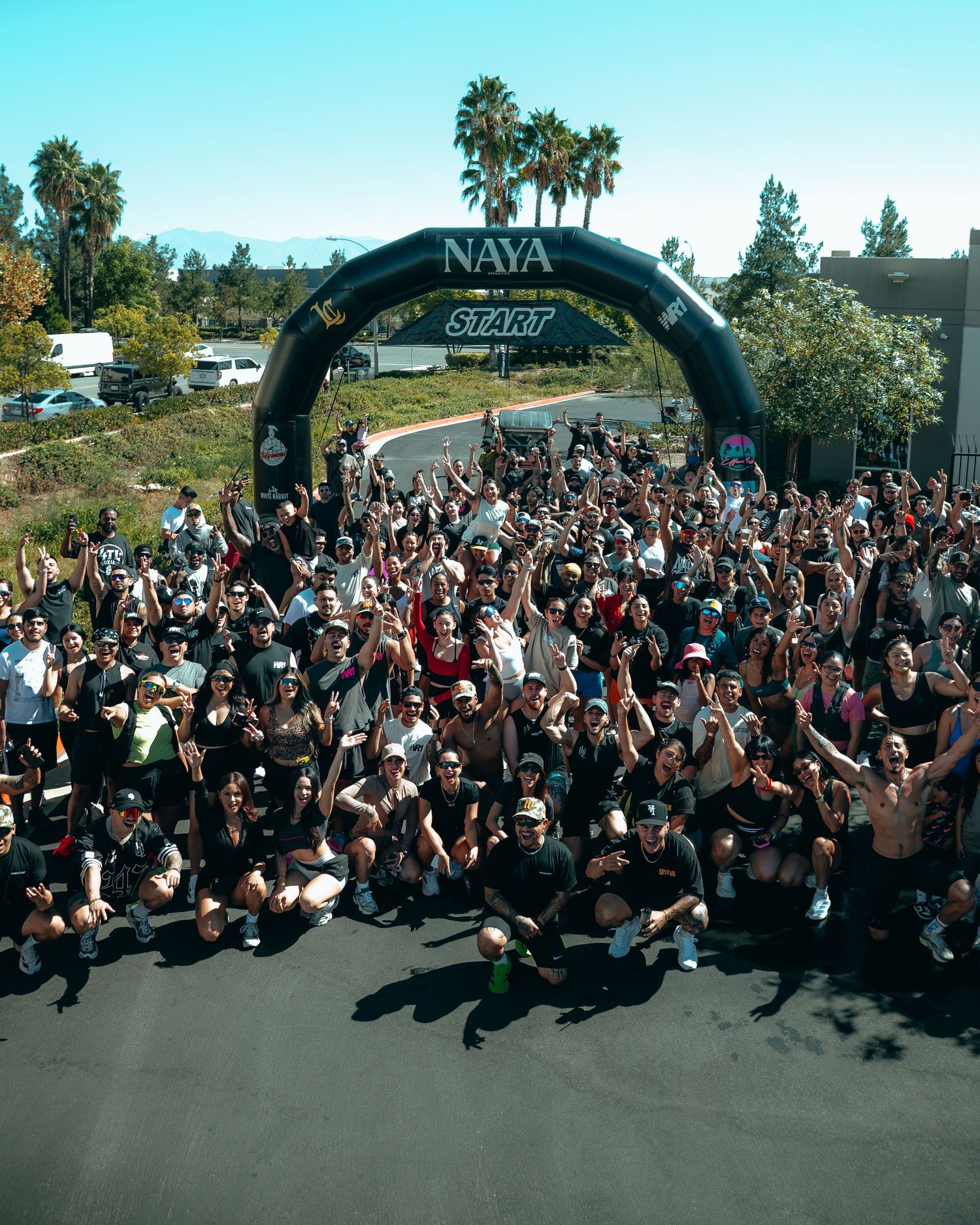 Large crowd of participants gathered under a NAYA start arch at an outdoor running event.