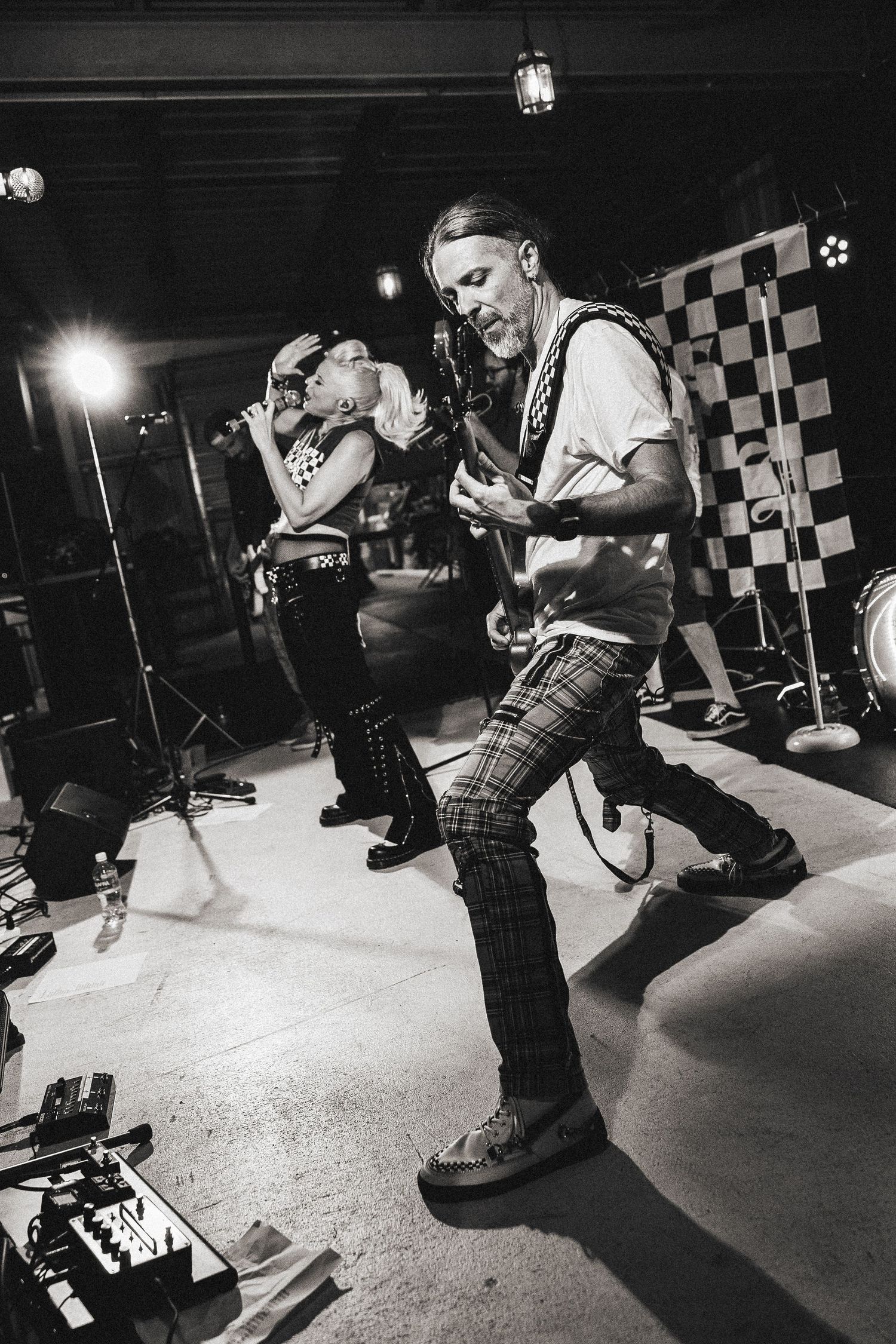 Male guitarist and female vocalist perform energetically on stage in black and white photo.