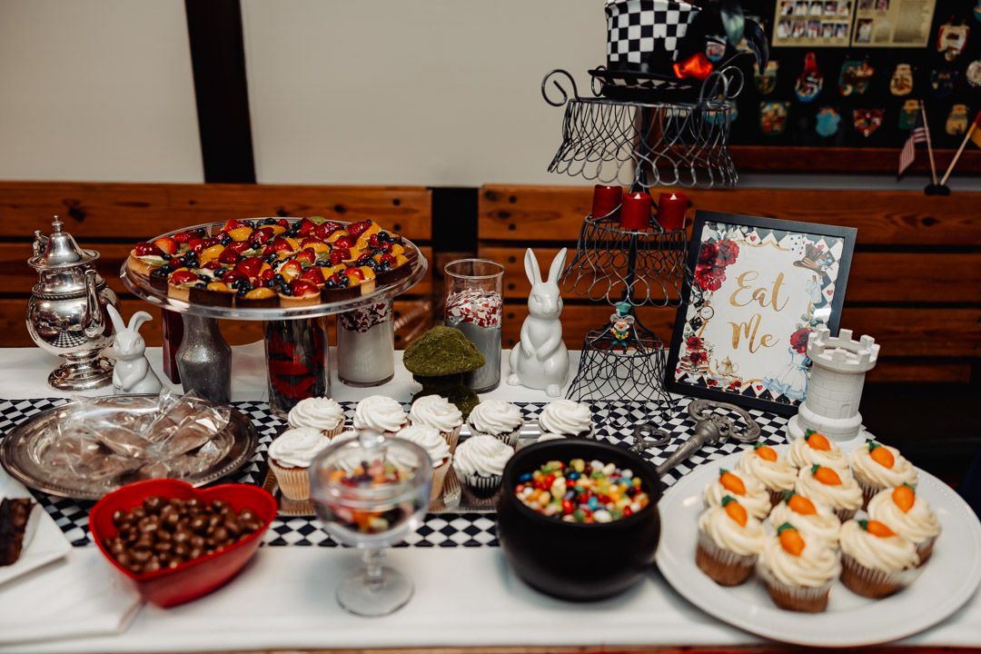 An elegant dessert table with various sweets, cakes and treats arranged on white pedestals and stands.