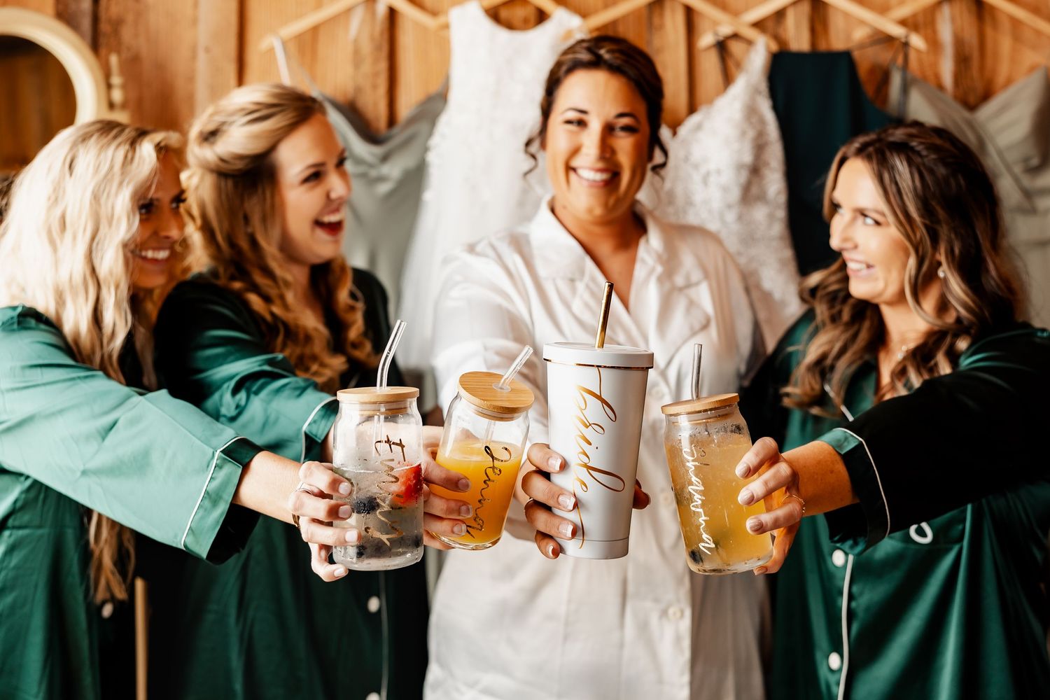 Friends in matching green robes toasting and celebrating with drinks before a wedding ceremony.