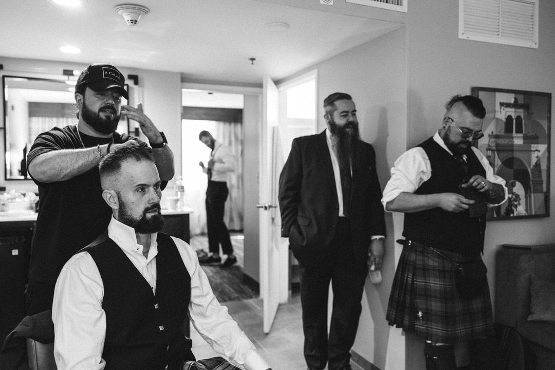 Black and white image of wedding preparation with stylists working.