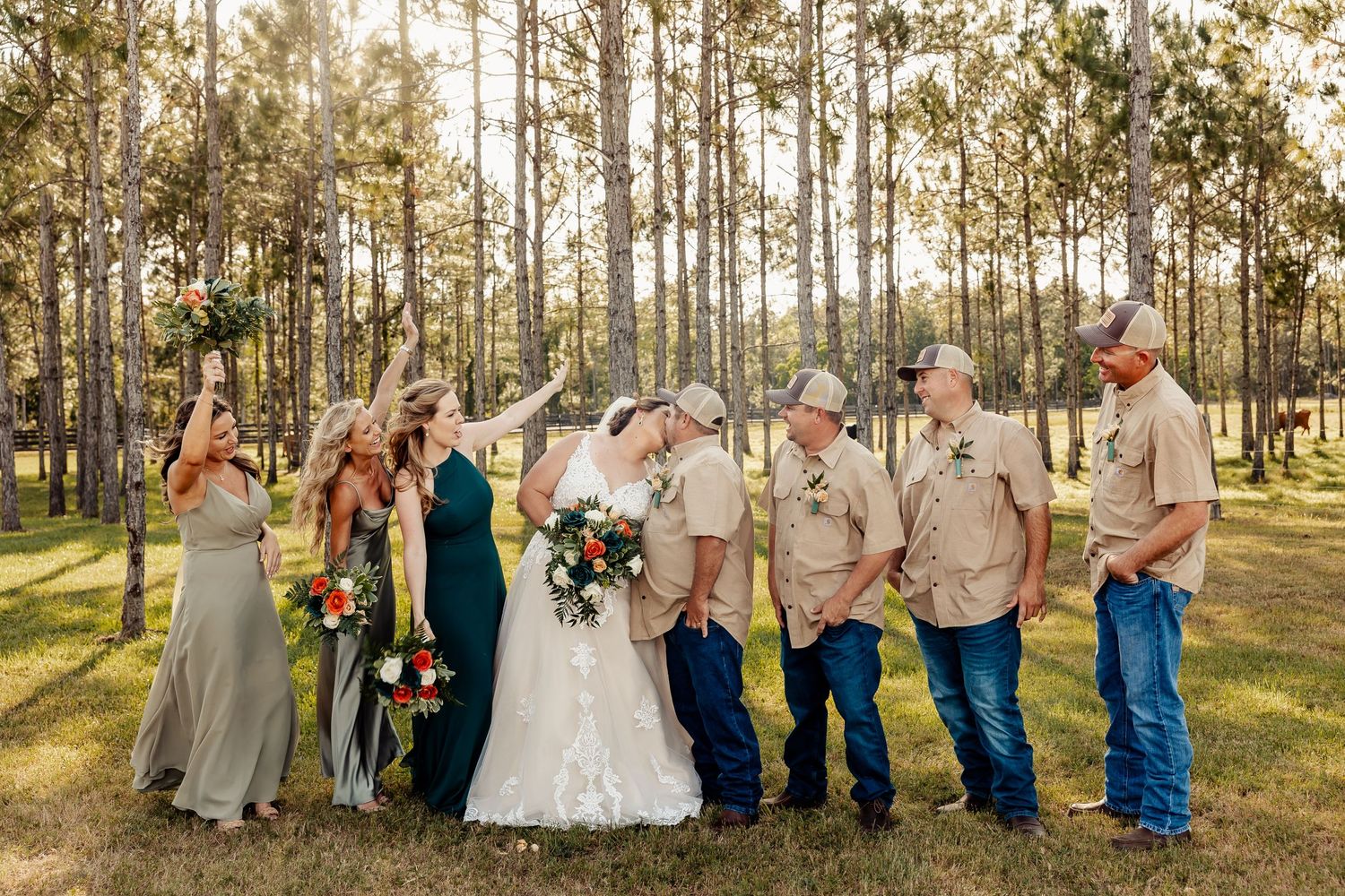 Wedding party gathered in a sun-dappled forest for casual group photos.