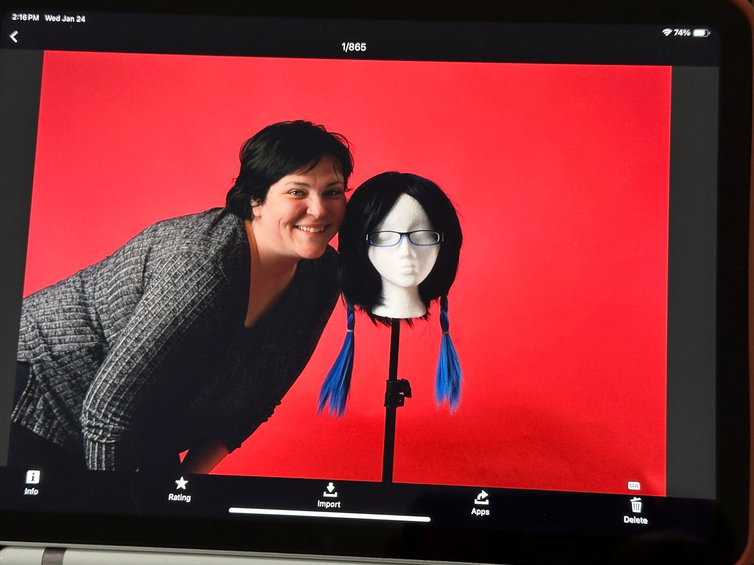 Portrait setup with mannequin head wearing dark wig against bright red backdrop.