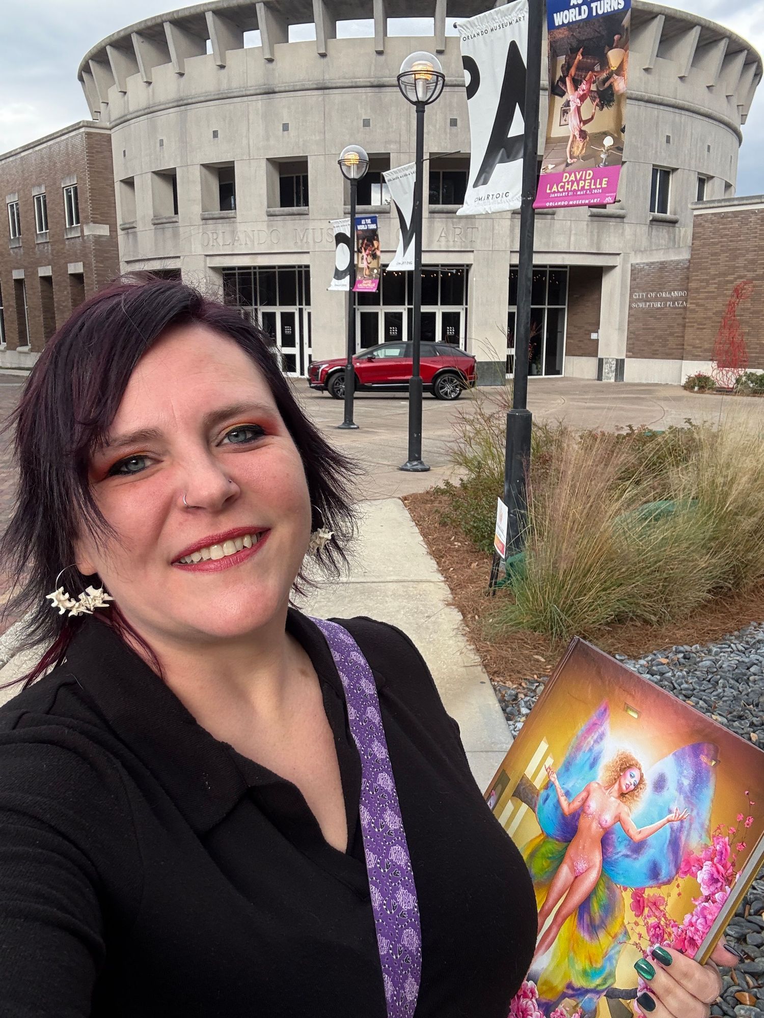 Someone shows off a colorful rainbow vinyl record sleeve with abstract artwork against a brick building background.