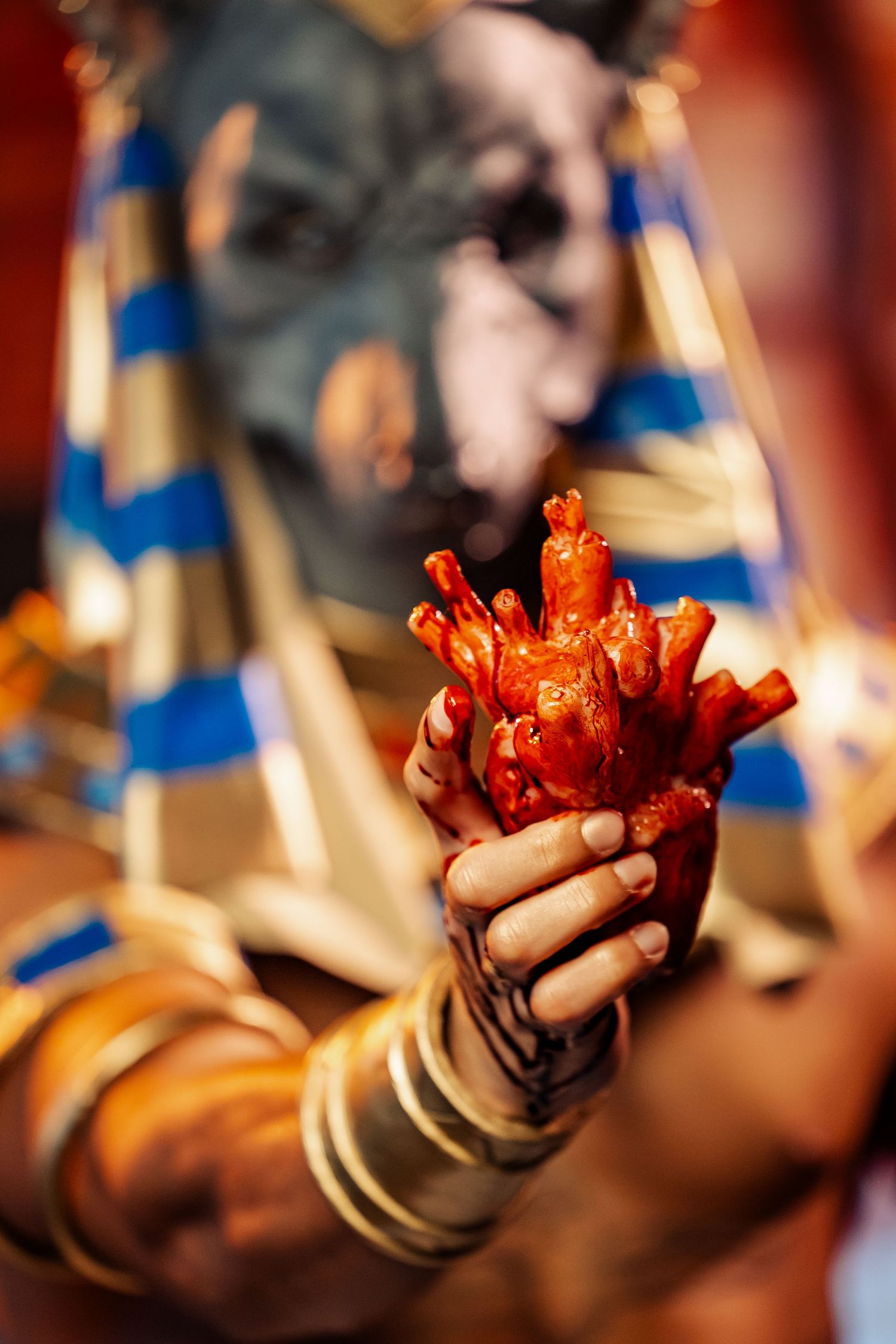Close-up shot of hands in gold bracers holding red crystal props against Egyptian costume.