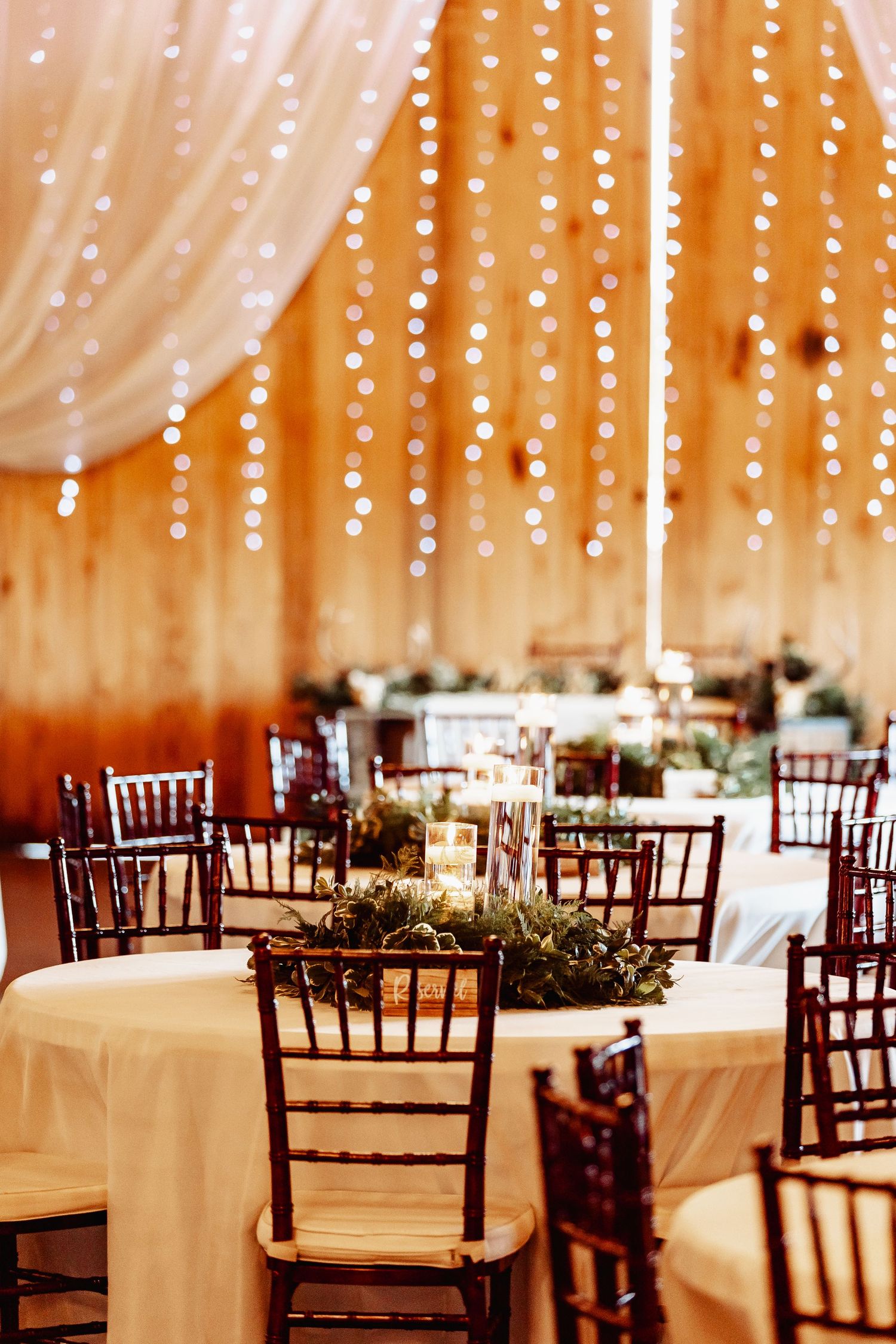 Wedding reception venue with string lights and Chiavari chairs creating a romantic atmosphere.